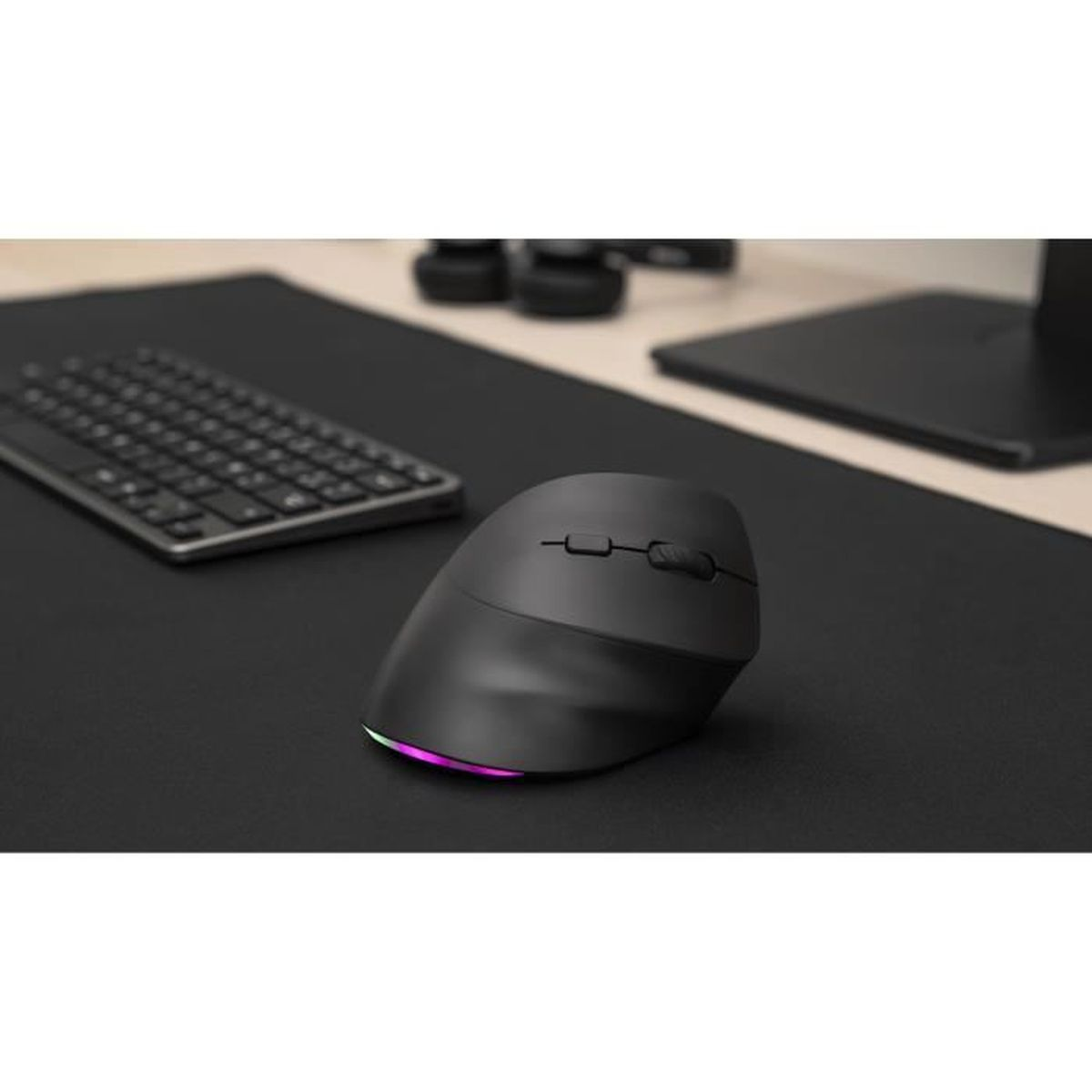 Eine schwarze ergonomische Maus mit RGB-Beleuchtung sitzt auf einem schwarzen Mauspad neben einer Tastatur.