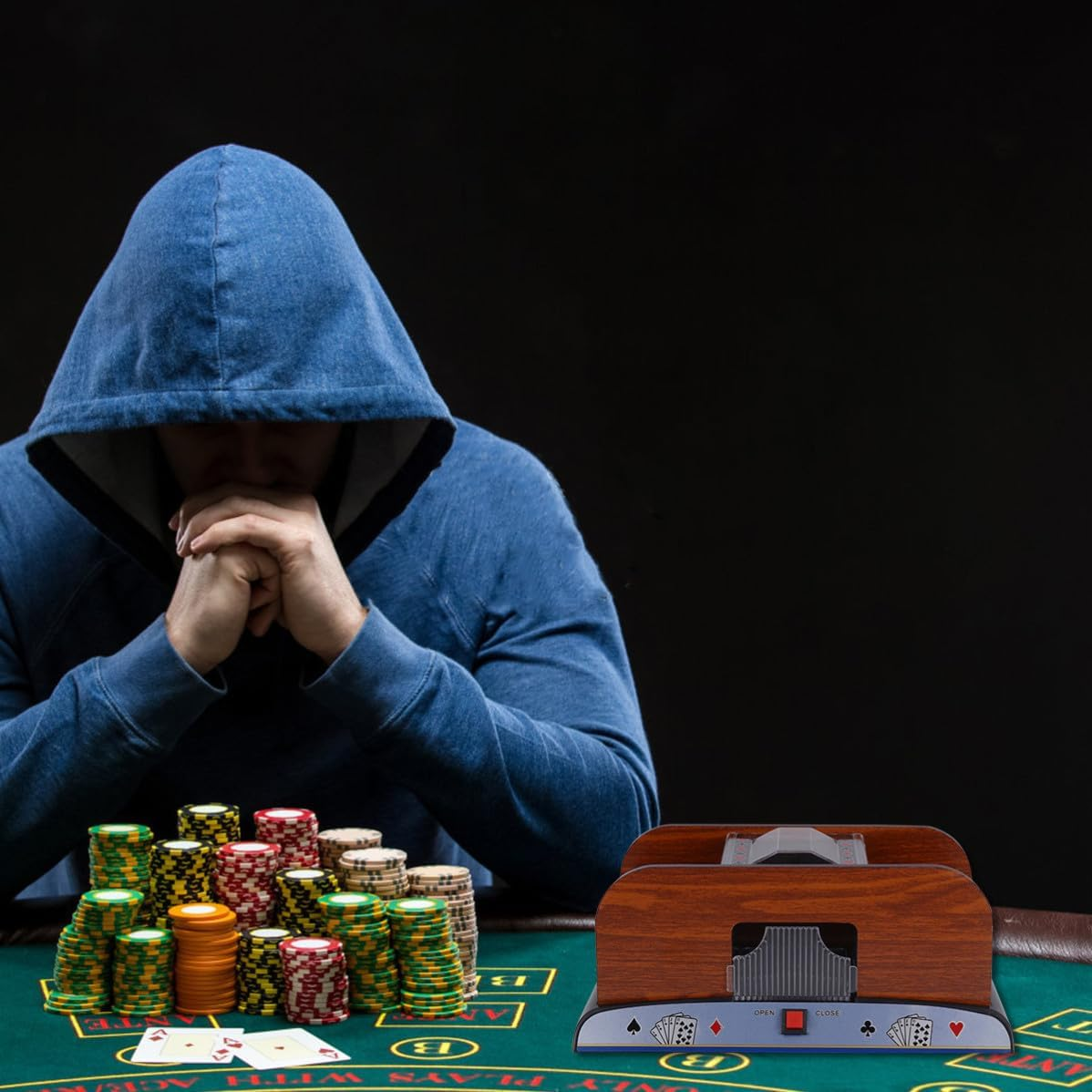 Ein Mann im blauen Hoodie sitzt an einem Pokertisch mit Chips und Karten.