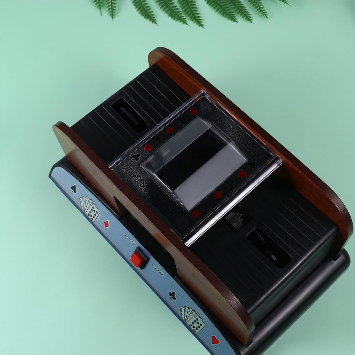Ein automatischer Kartenmischer aus Holz und schwarzem Kunststoff mit Kartenmotiven.