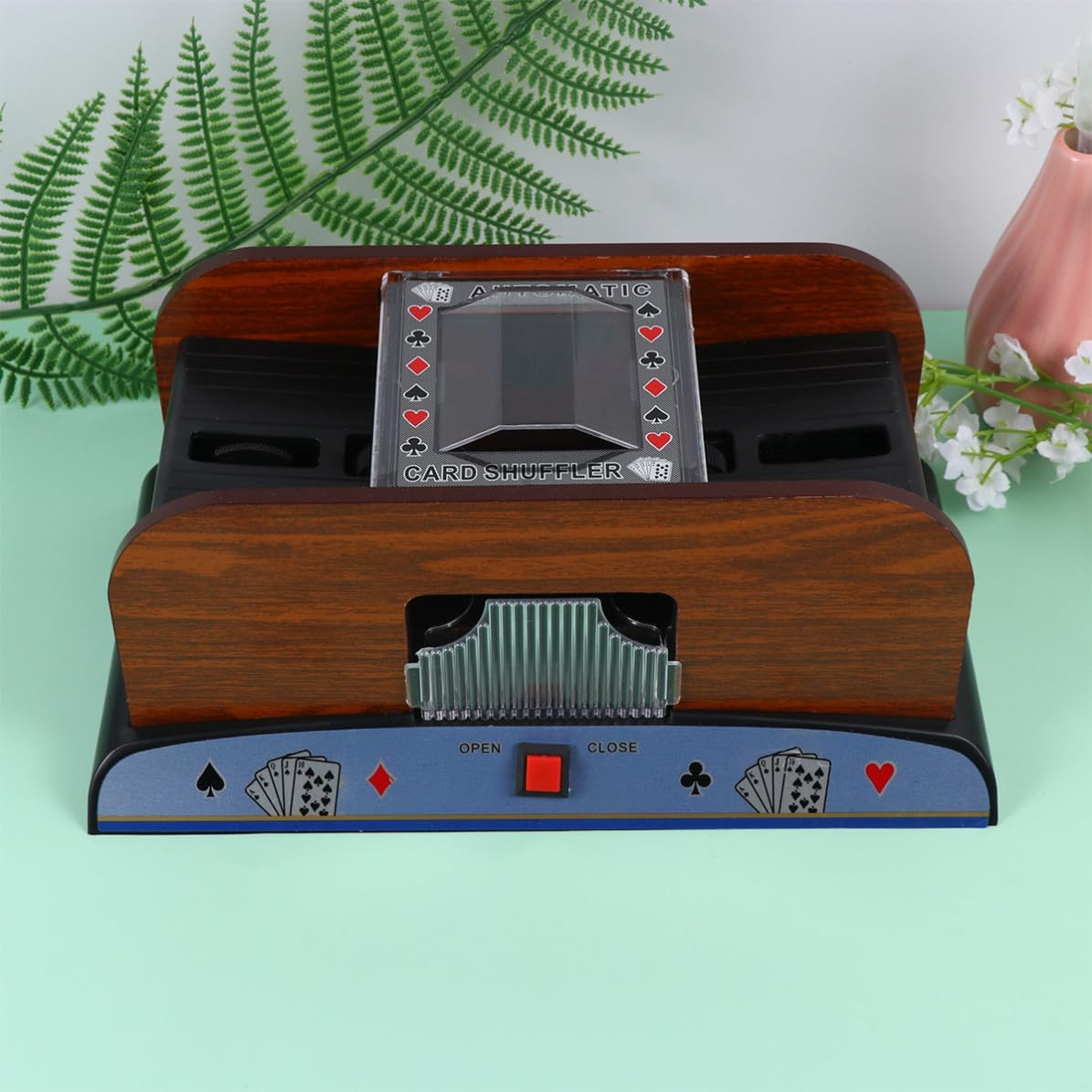 Ein automatischer Kartenmischer aus Holz mit einem transparenten Deckel und Kartensymbolen.