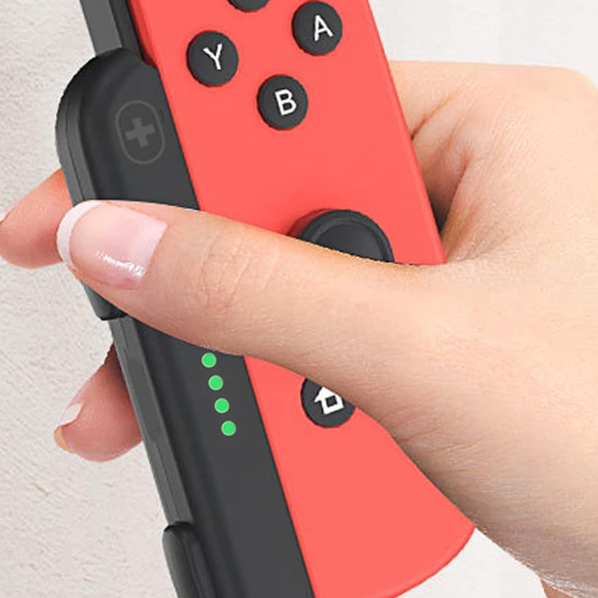 Eine Hand hält einen roten Gamecontroller mit den Tasten Y, A, B und einem Joystick.