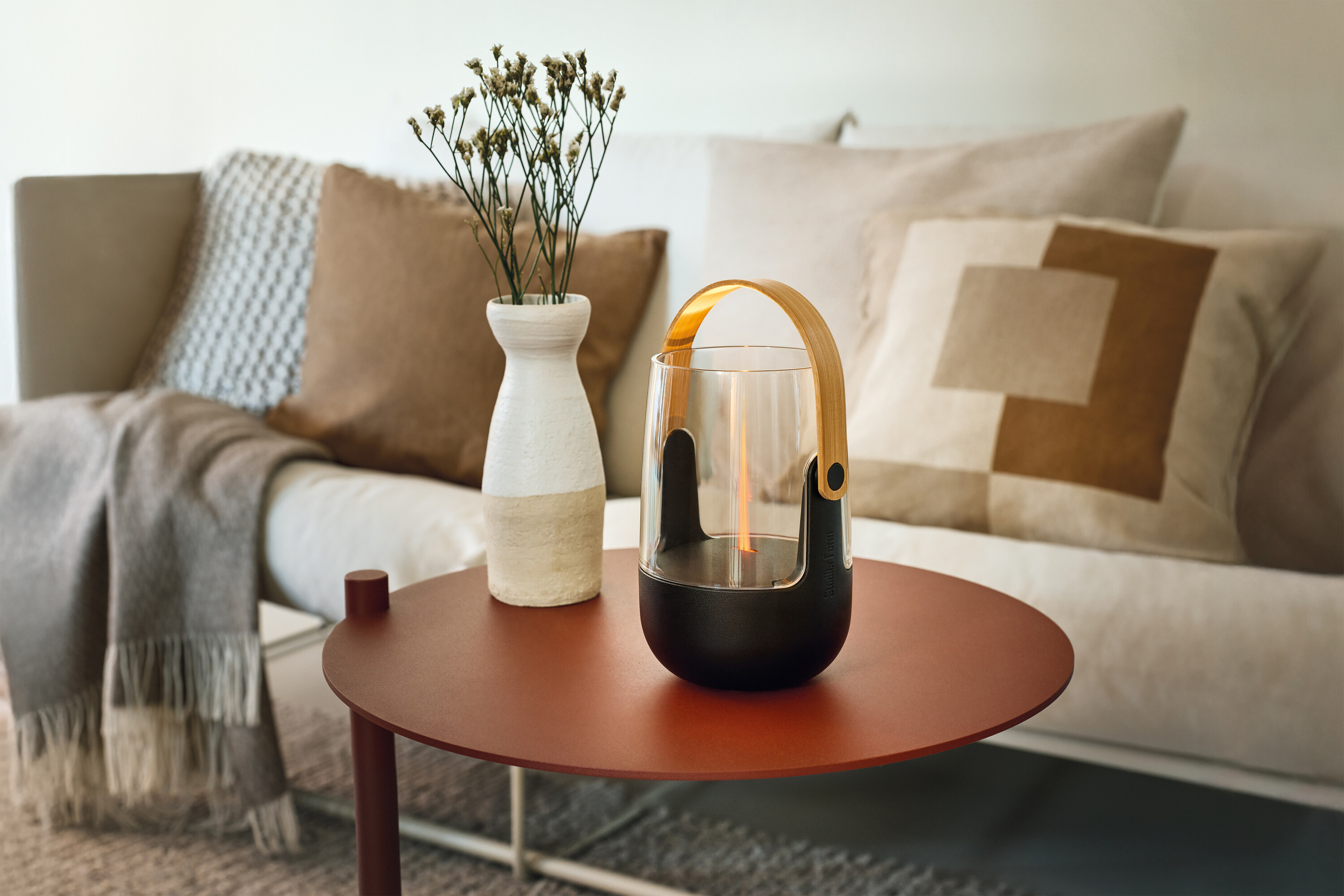 A modern table with a lamp and a vase of dried flowers.
