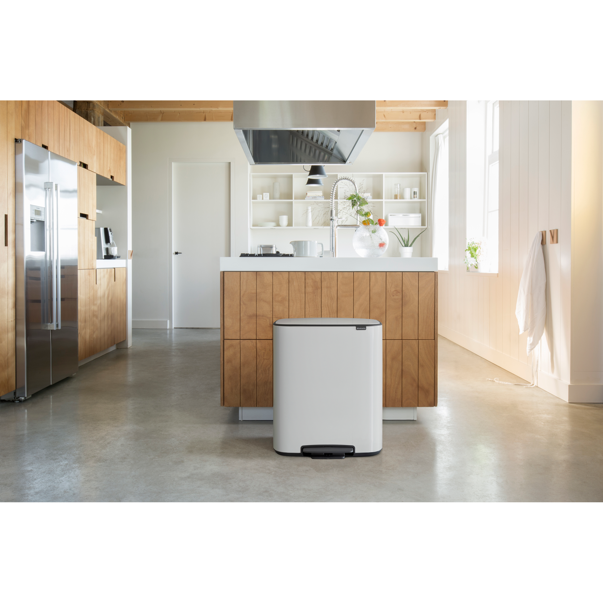 Moderne keuken met roestvrijstalen koelkast, houten accenten en witte prullenbak.