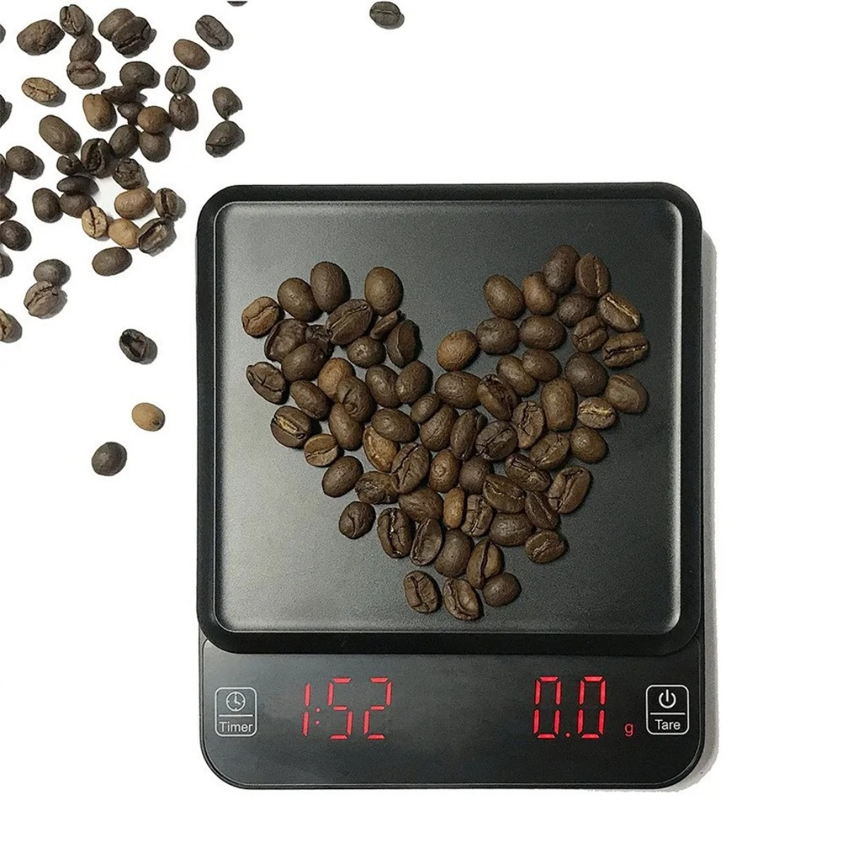 Geröstete Kaffeebohnen bilden ein Herz auf einer Digitalwaage neben verstreuten Bohnen.