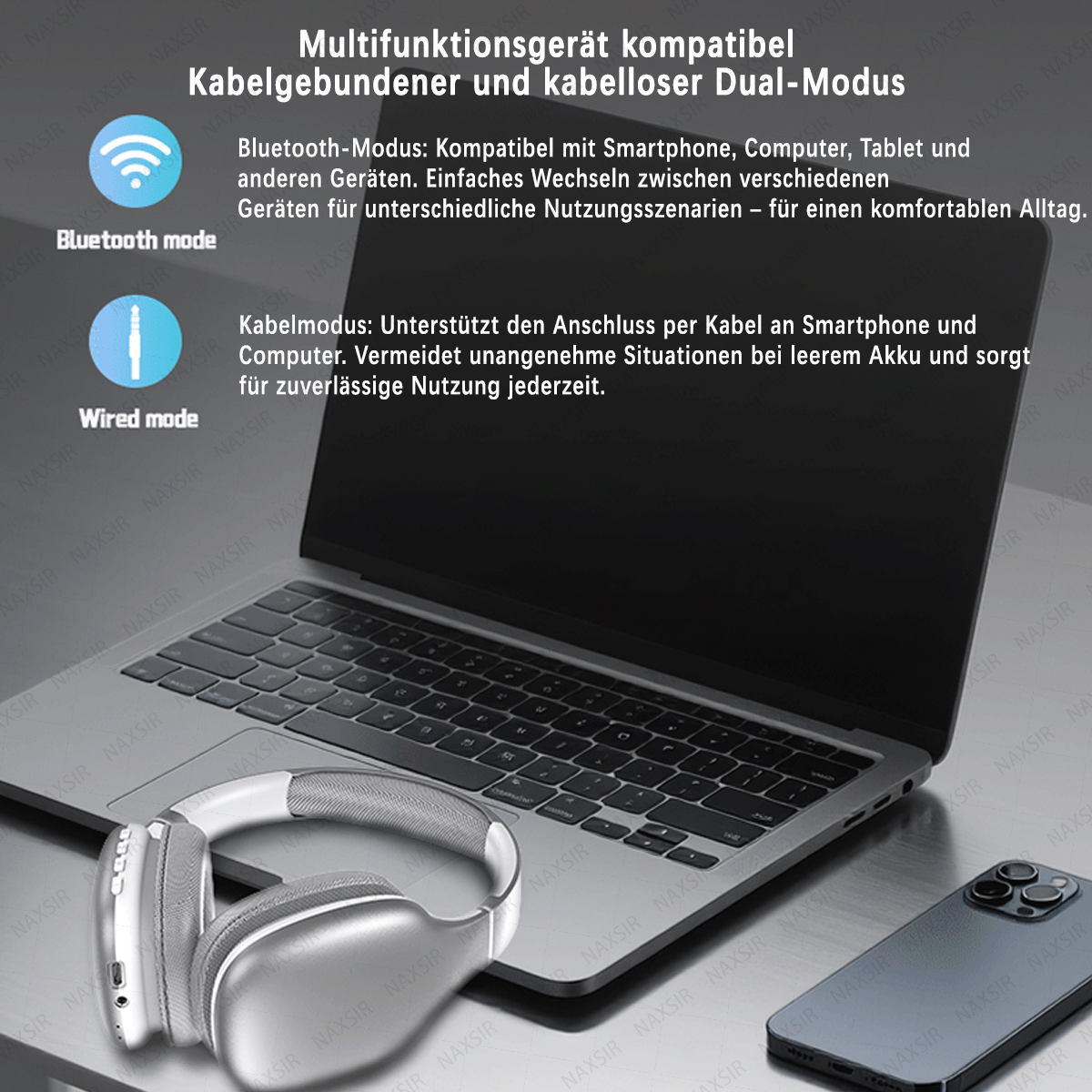 Silberne Kopfhörer, ein Laptop und ein Smartphone liegen auf einem Tisch.