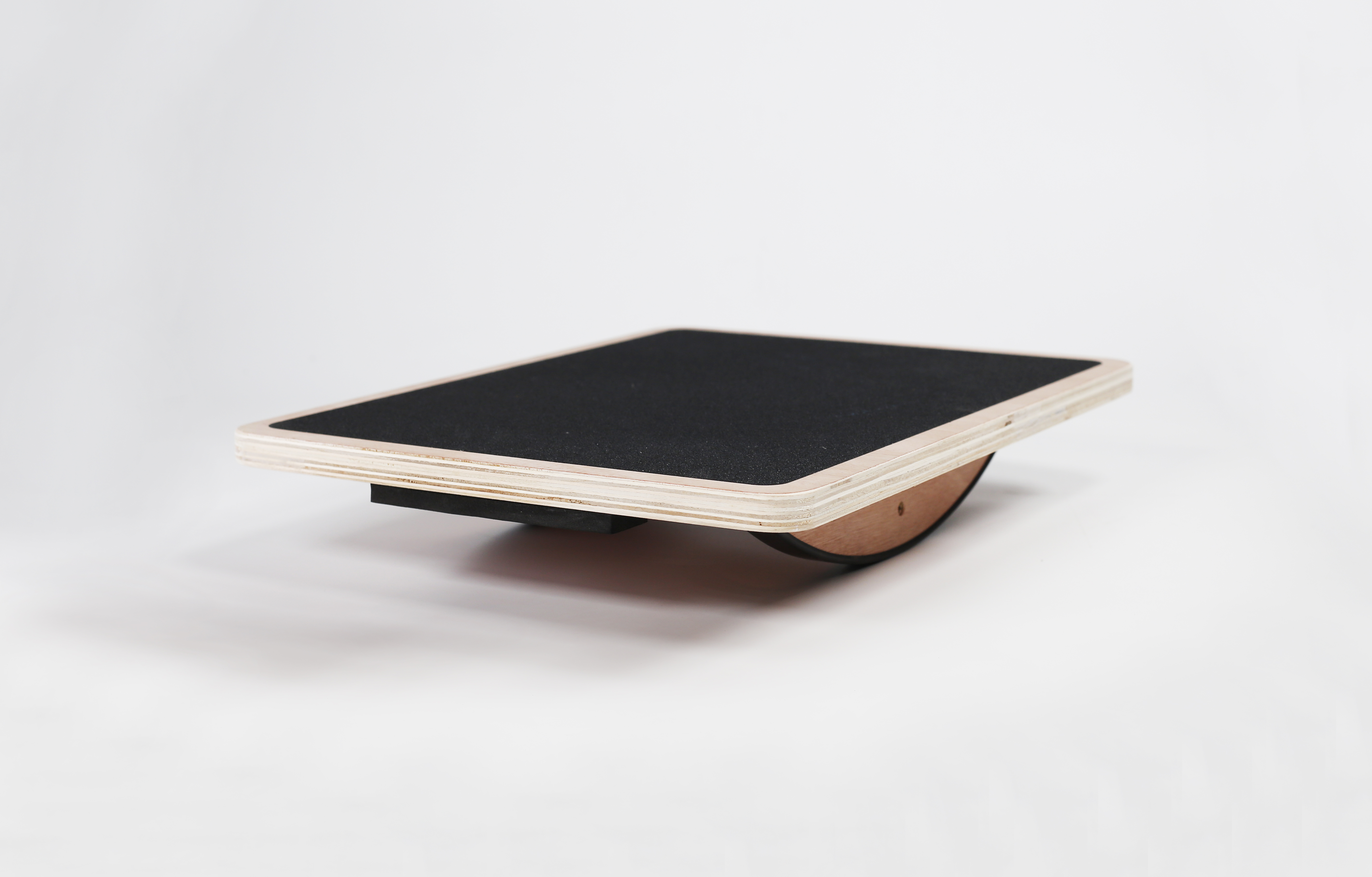 Una tavola di equilibrio in legno con superficie nera e un rullo sotto.
