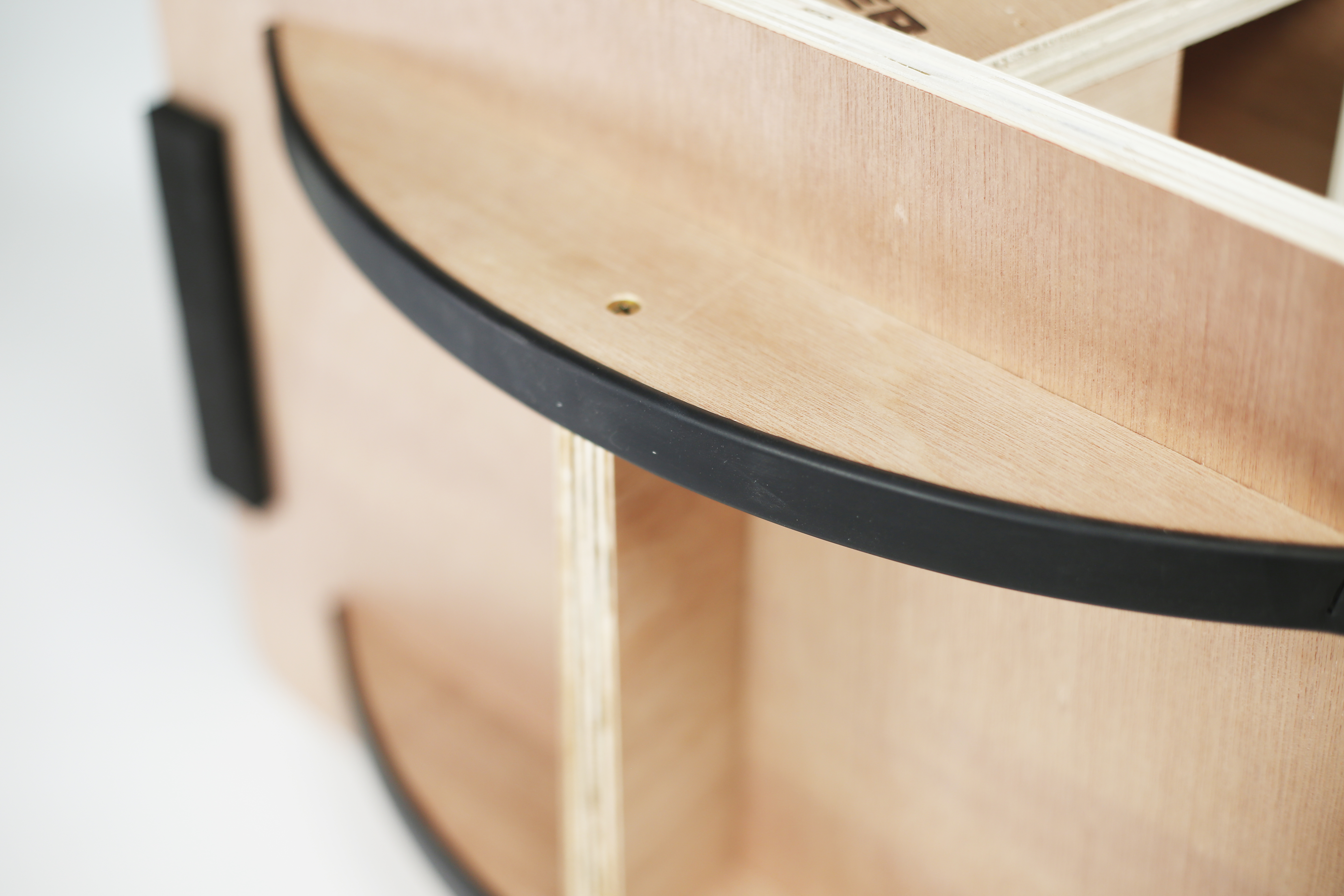 Cassa in legno con bordo nero e vite visibile.