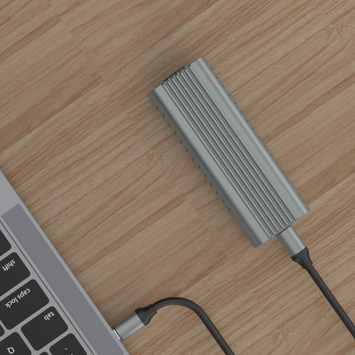 Un adaptador gris conecta una laptop a un cable sobre una superficie de madera.