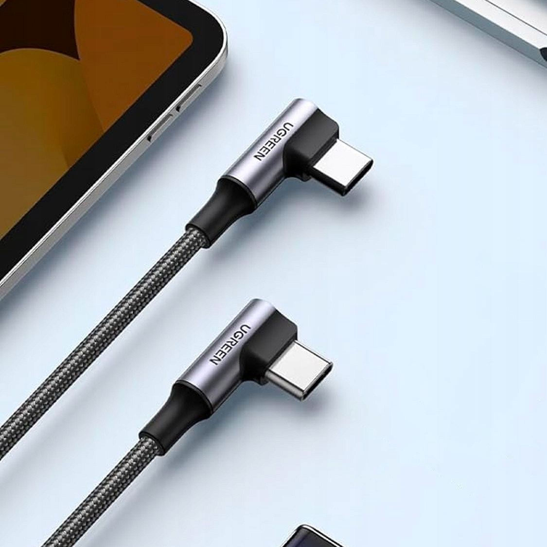 Due cavi di ricarica UGREEN USB-C con connettori angolati di 90 gradi giacciono su una superficie blu.
