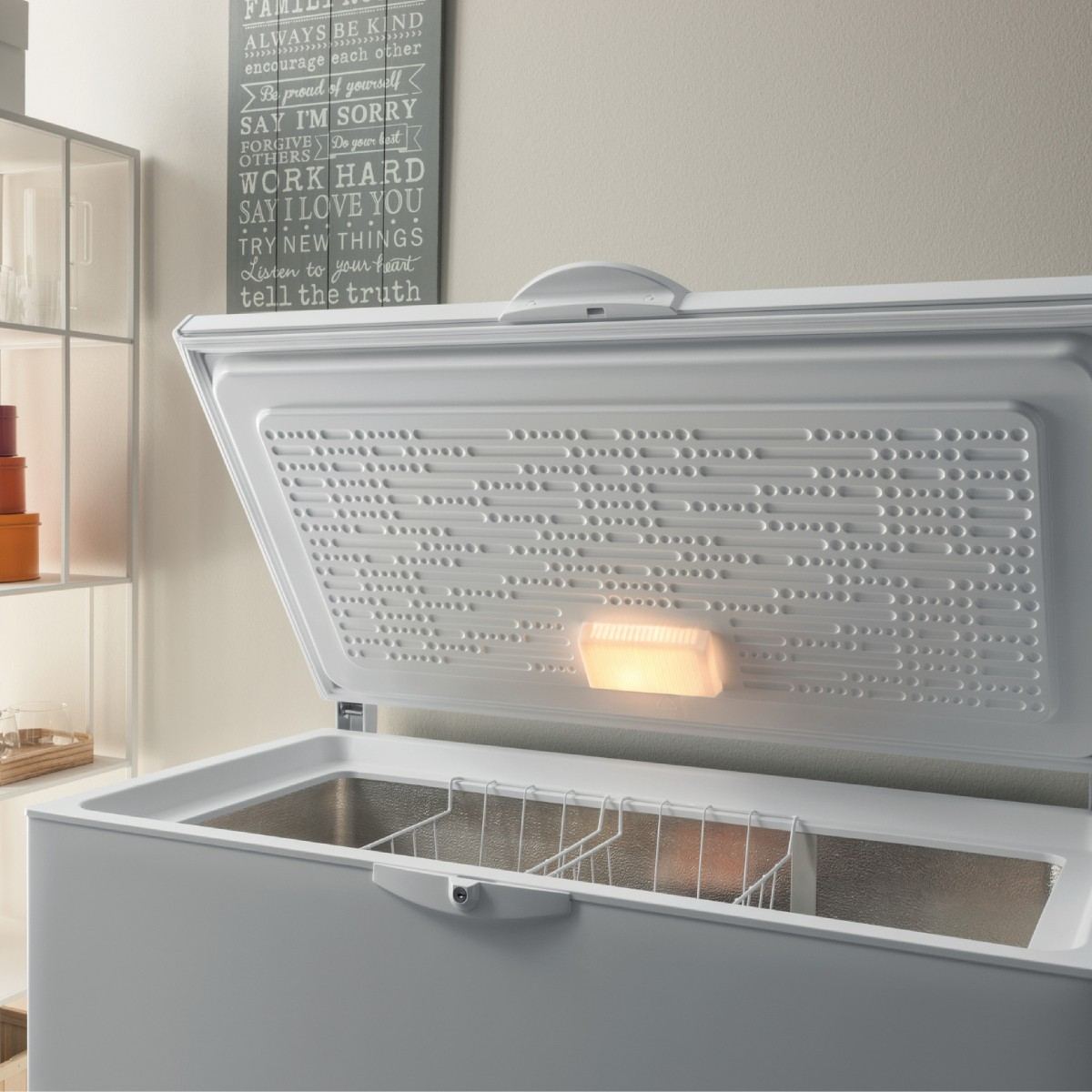 Un congelatore a pozzetto bianco aperto con luce interna e cestelli.