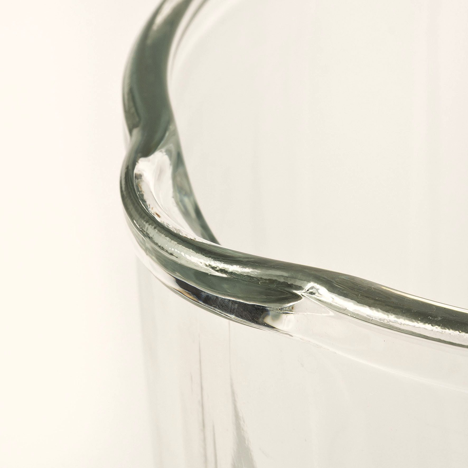 Nahaufnahme des Randes eines klaren Glases mit gedrehten Details.