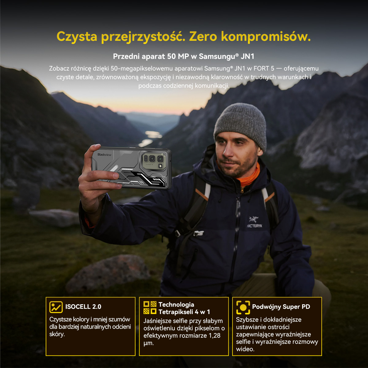Mężczyzna z plecakiem robi selfie w górskim krajobrazie z telefonem.
