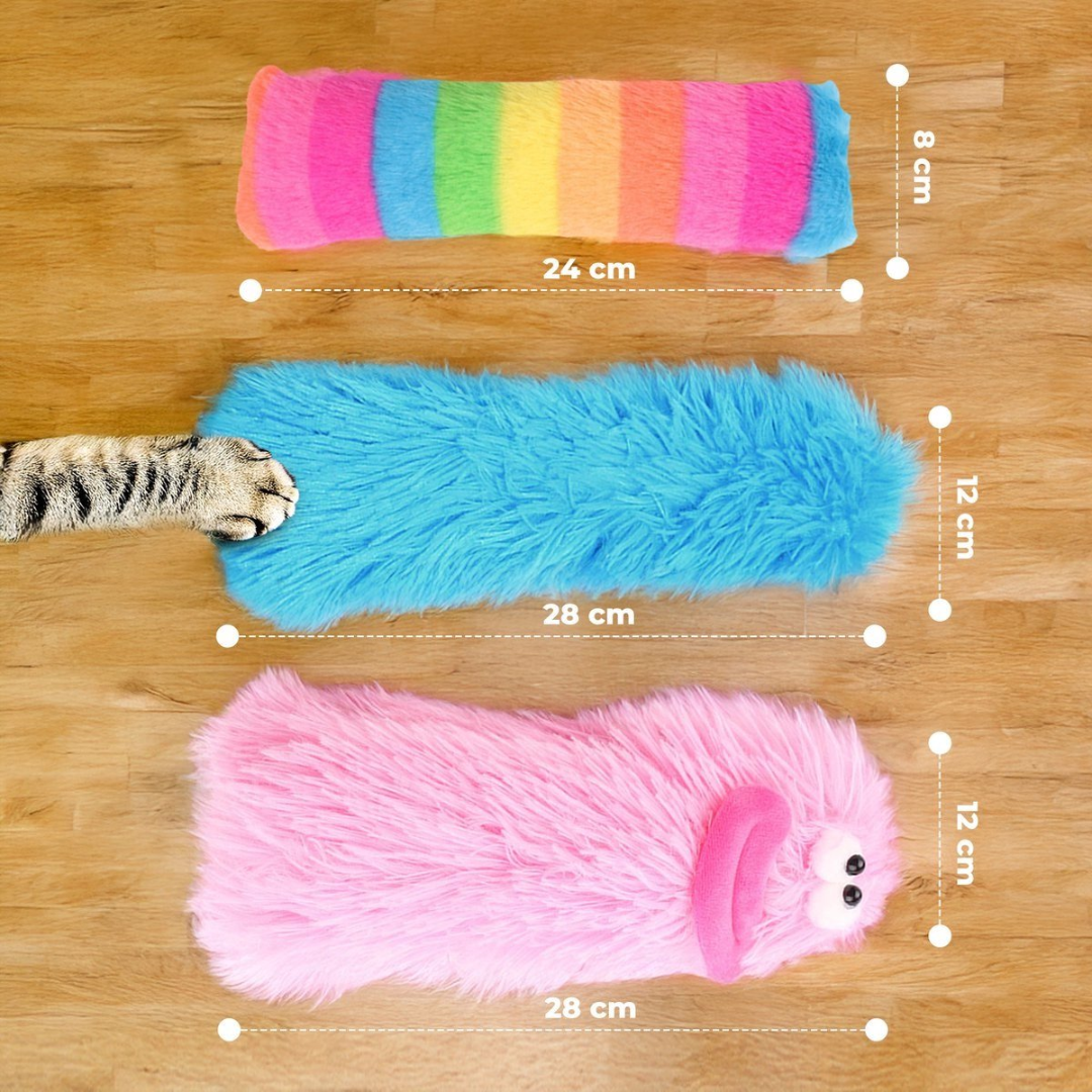 Three fluffy cat toys on a wooden floor. One is a rainbow, another blue with a cat paw.