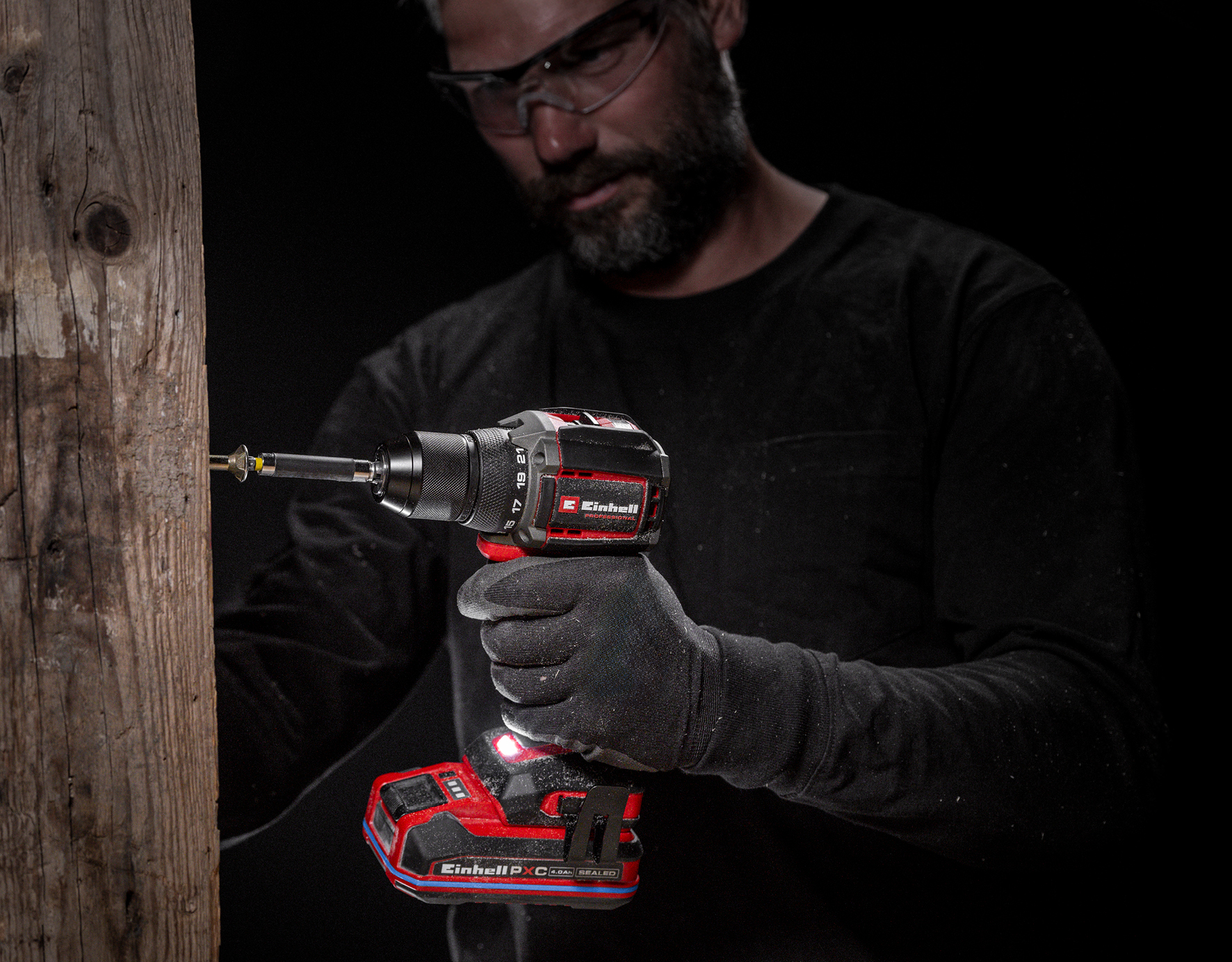 Mann mit Schutzbrille bohrt mit Akkuschrauber in Holz.