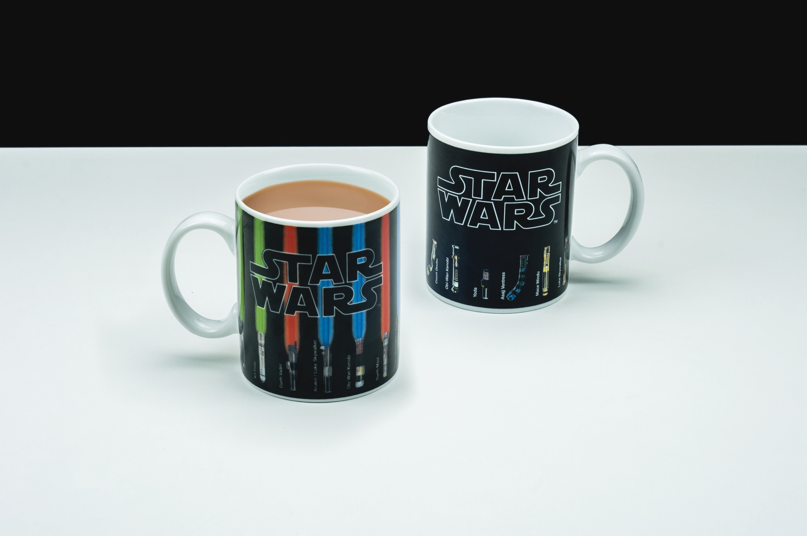 Dwa kubki Star Wars, jeden wypełniony brązowym płynem, na białym stole.
