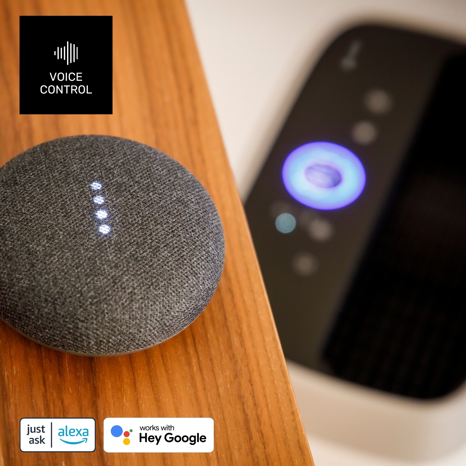 Un altavoz Google Nest Mini gris con luces encendidas, junto a un dispositivo negro. Se ven logotipos de control por voz.