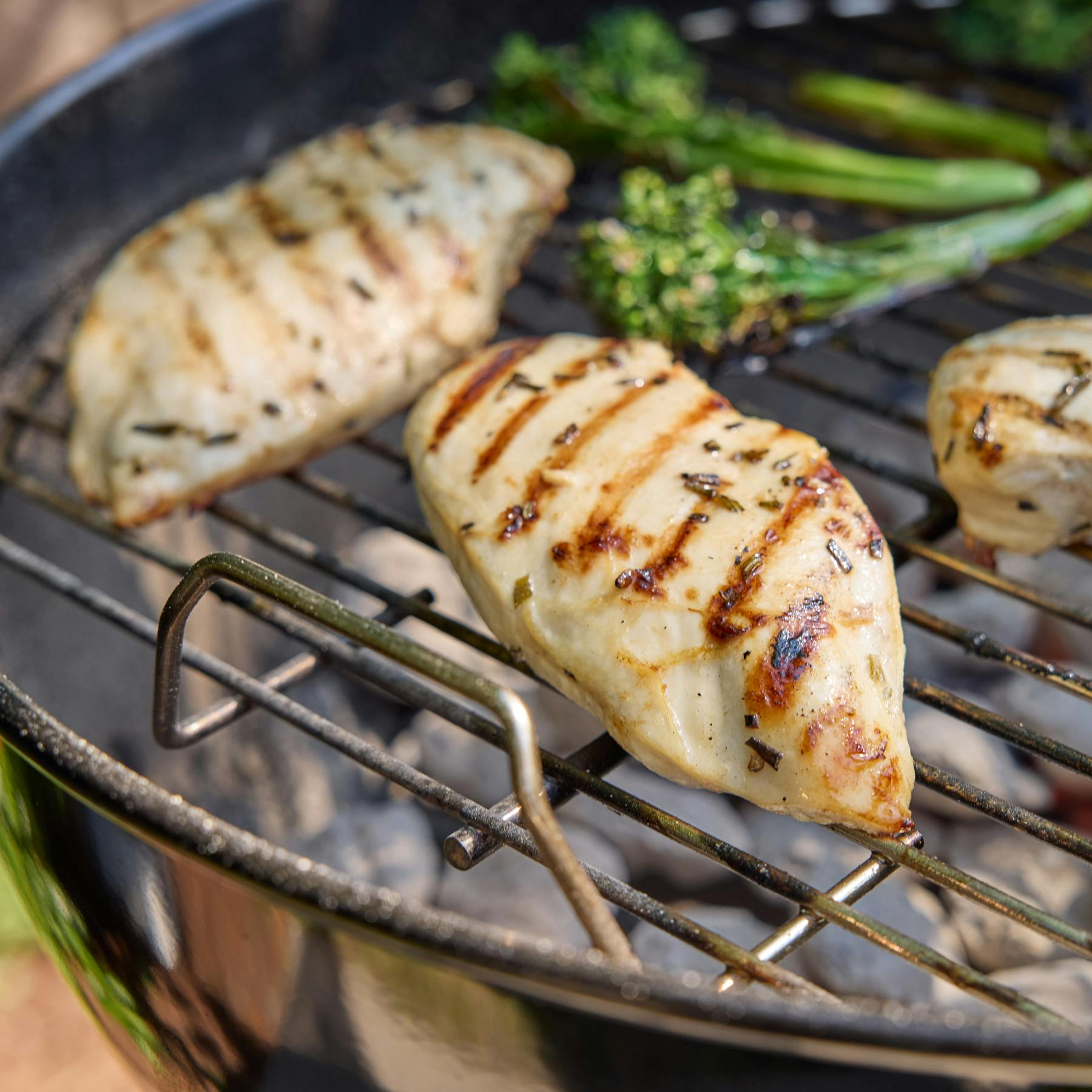 Gegrillte Hähnchenbrust mit Brokkoli auf einem Holzkohlegrill.