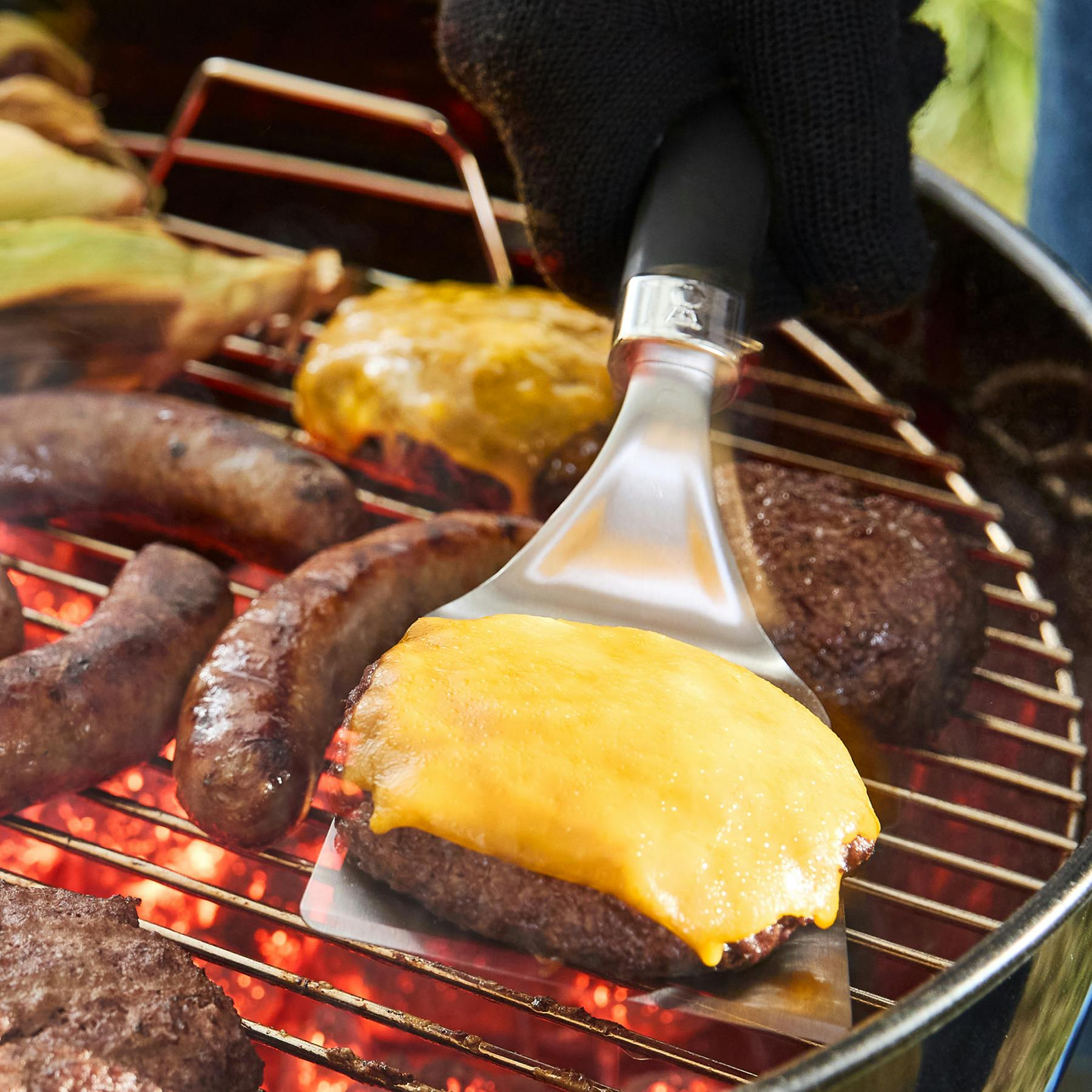 Fleisch und Wurst brutzeln auf einem Grill mit glühenden Kohlen.