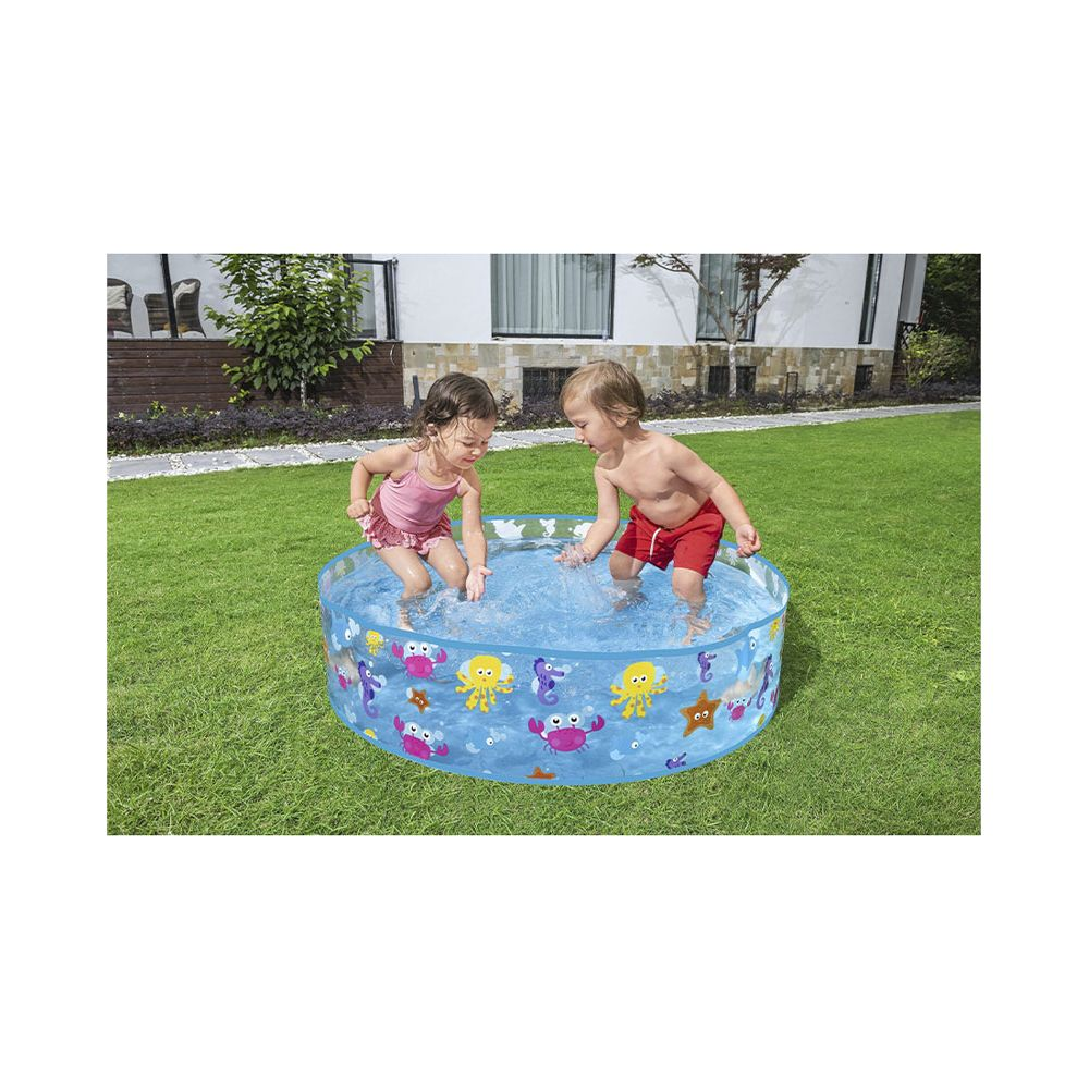 Dos niños chapotean en una piscina inflable azul con criaturas marinas en un jardín.