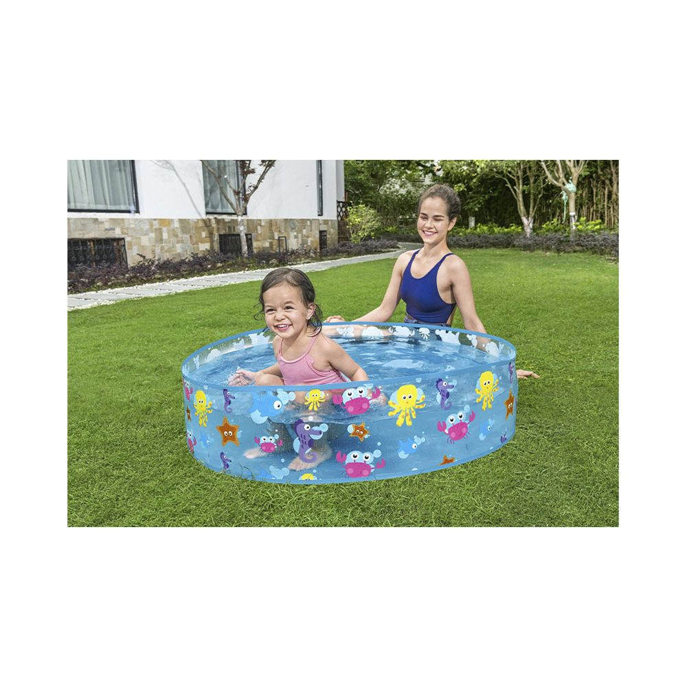 Una niña y una mujer chapotean en una piscina inflable con criaturas marinas en un jardín.