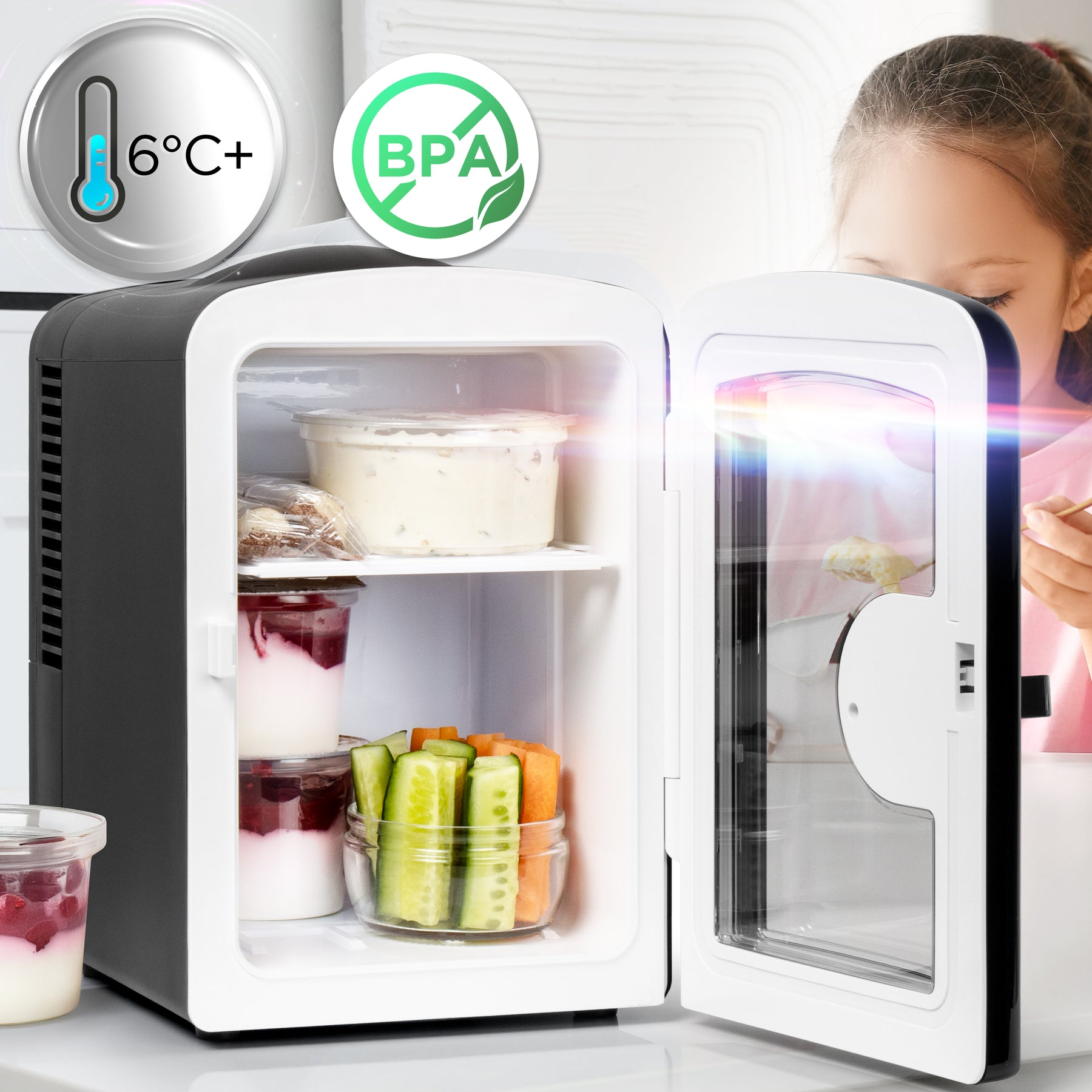 Ein kleiner Kühlschrank mit geöffneter Tür, gefüllt mit Joghurt, Obst und Gemüse.