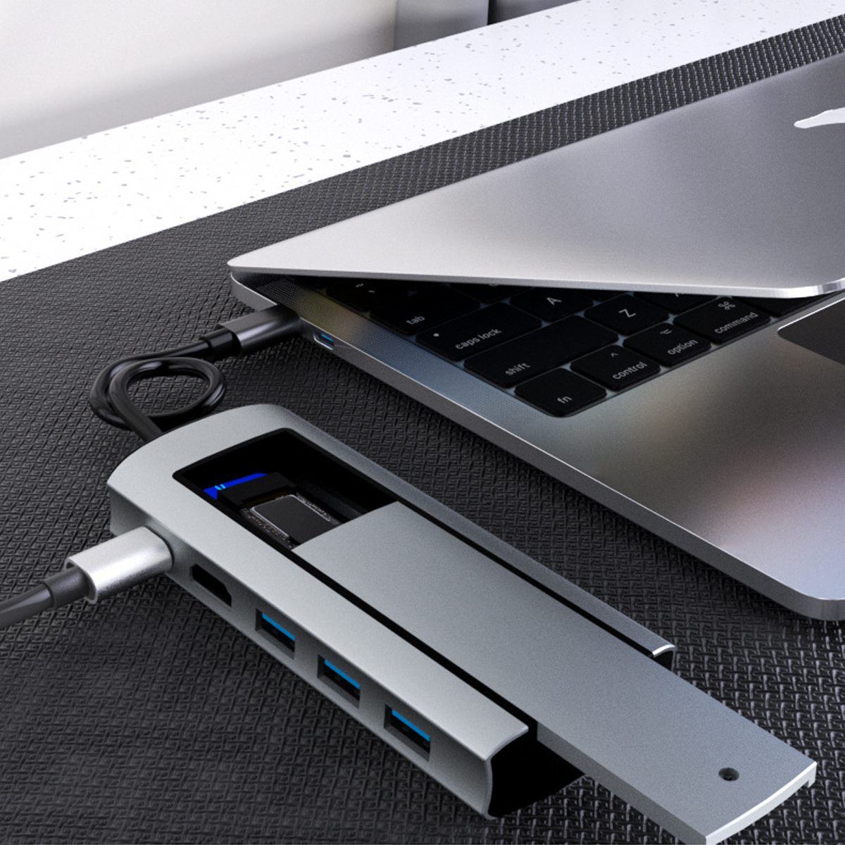Ein silberner USB-Hub mit mehreren Anschlüssen ist an einen silbernen Laptop auf einer schwarzen texturierten Oberfläche angeschlossen.