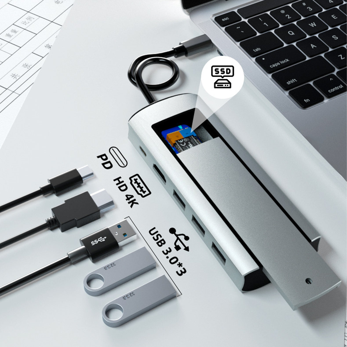 Ein silberner USB-Hub mit SSD-Steckplatz, an einen Laptop angeschlossen. Mit PD, HD 4K, USB 3.0 Anschlüssen.