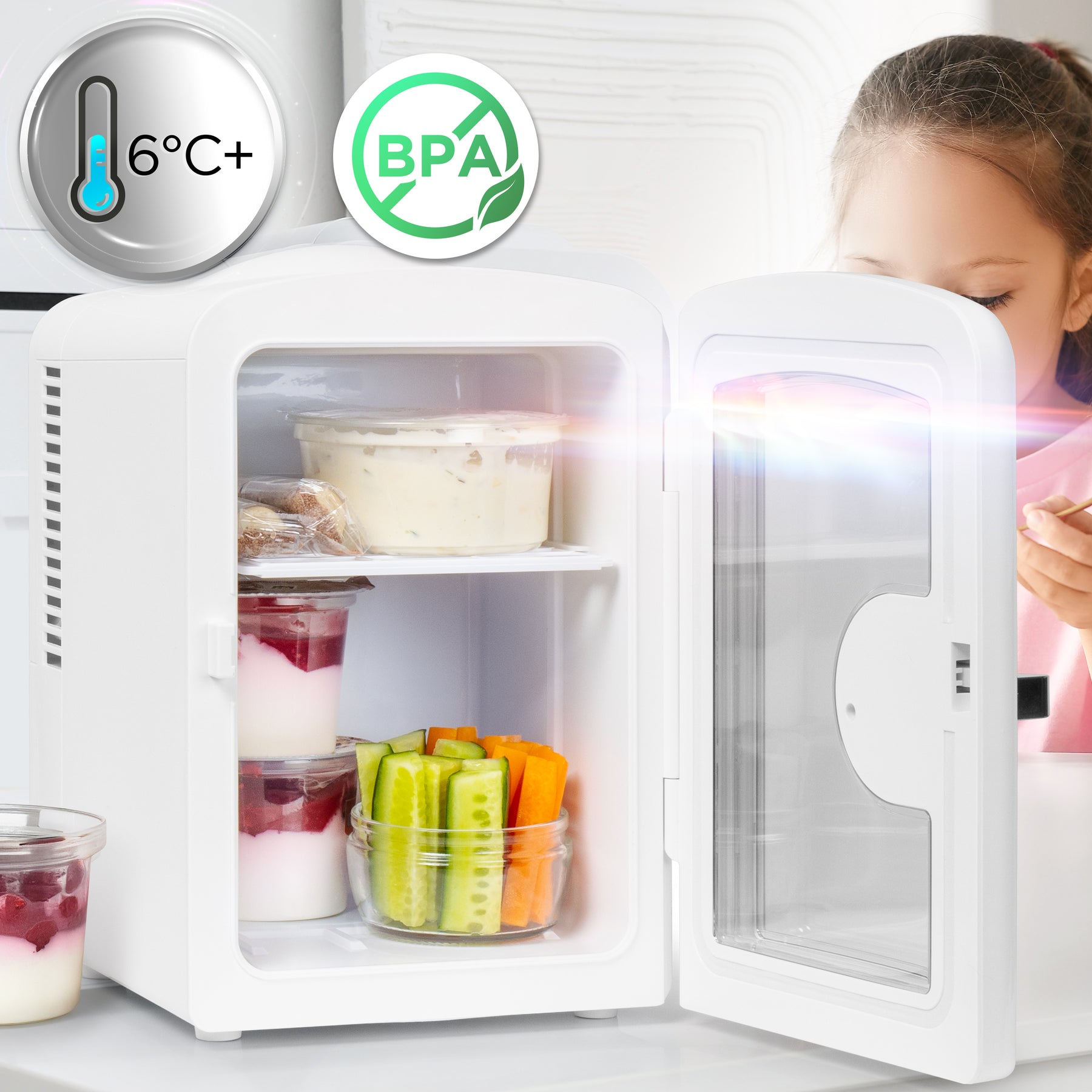 Ein offener weißer Mini-Kühlschrank mit Snacks und ein Mädchen im Hintergrund.