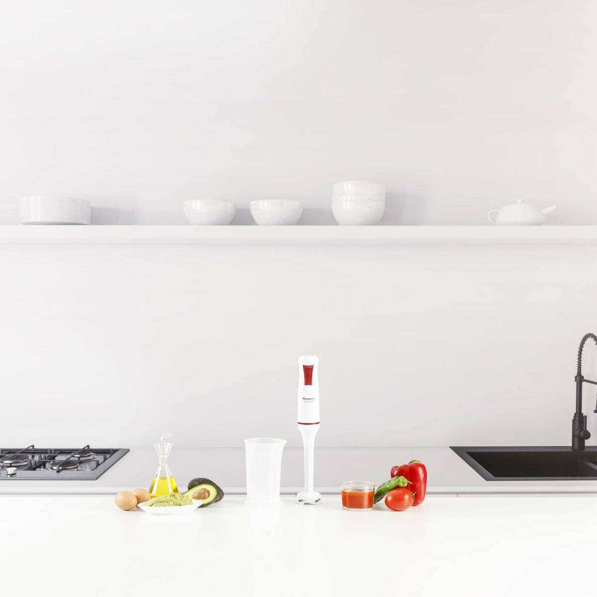 Ein weißer Stabmixer steht auf einer Küchentheke neben Zutaten wie Avocado, Eiern und Paprika.