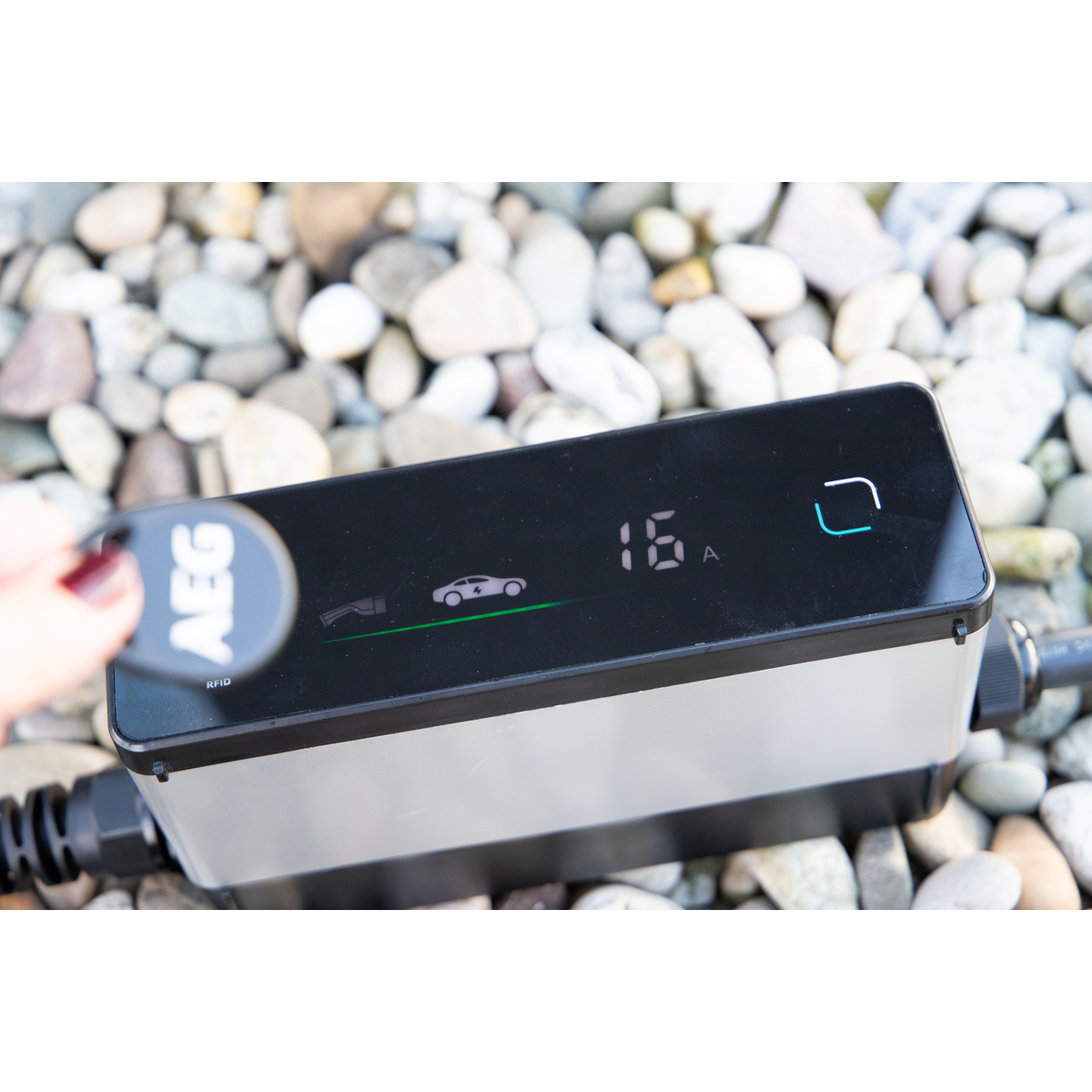 Ein AEG RFID-Schlüssel wird über einem Ladegerät für Elektroautos gehalten. 16A wird angezeigt.