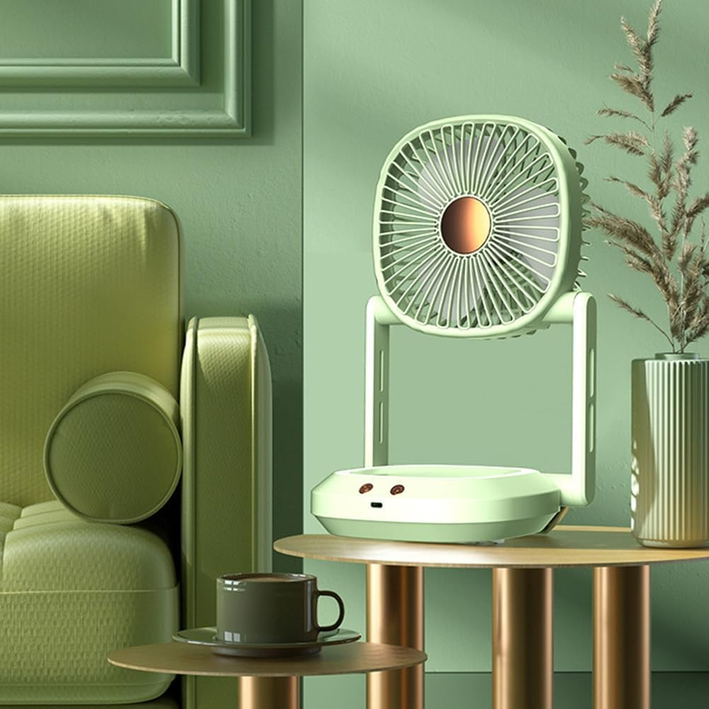 Ein grüner Schreibtischventilator steht auf einem Tisch neben einer Tasse Kaffee und einem Sofa.