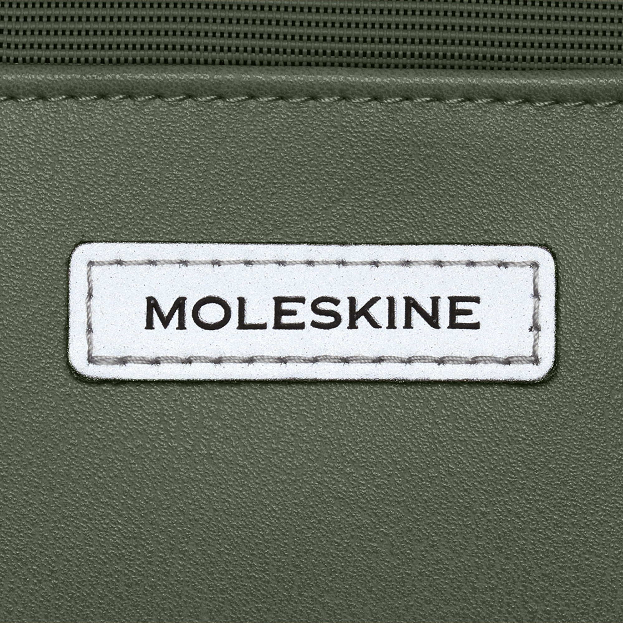 Etichetta verde con testo bianco Moleskine e cuciture.