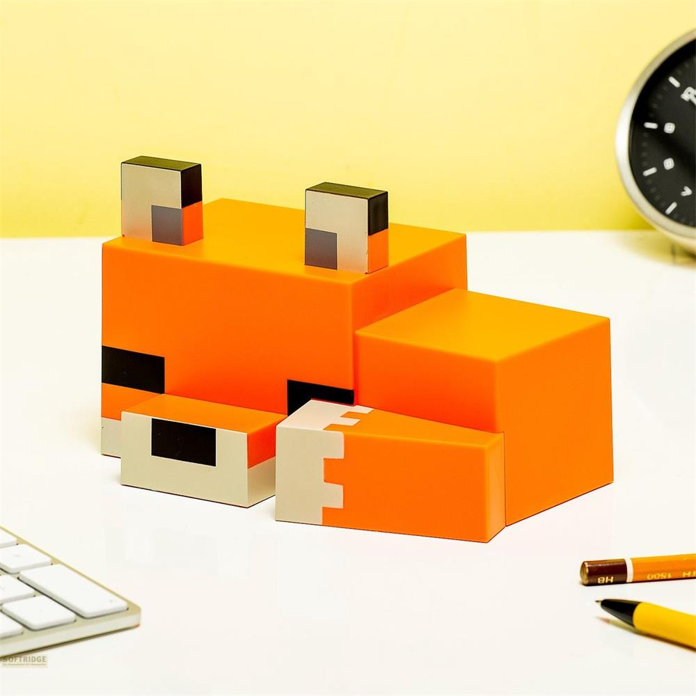 Ein orangefarbener Minecraft-Fuchs-Würfel auf einem Schreibtisch mit Tastatur und Stiften.