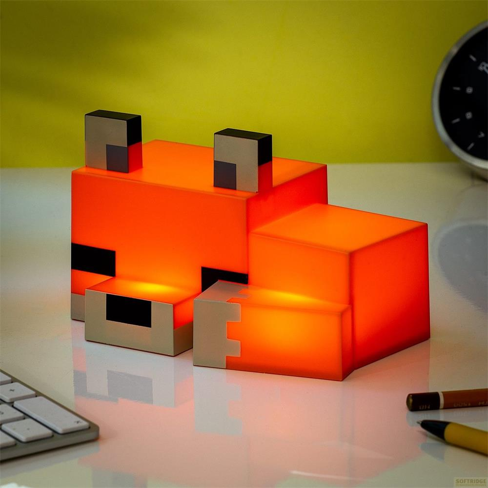 Eine orangefarbene, pixelige Fuchslampe leuchtet auf einem Schreibtisch.