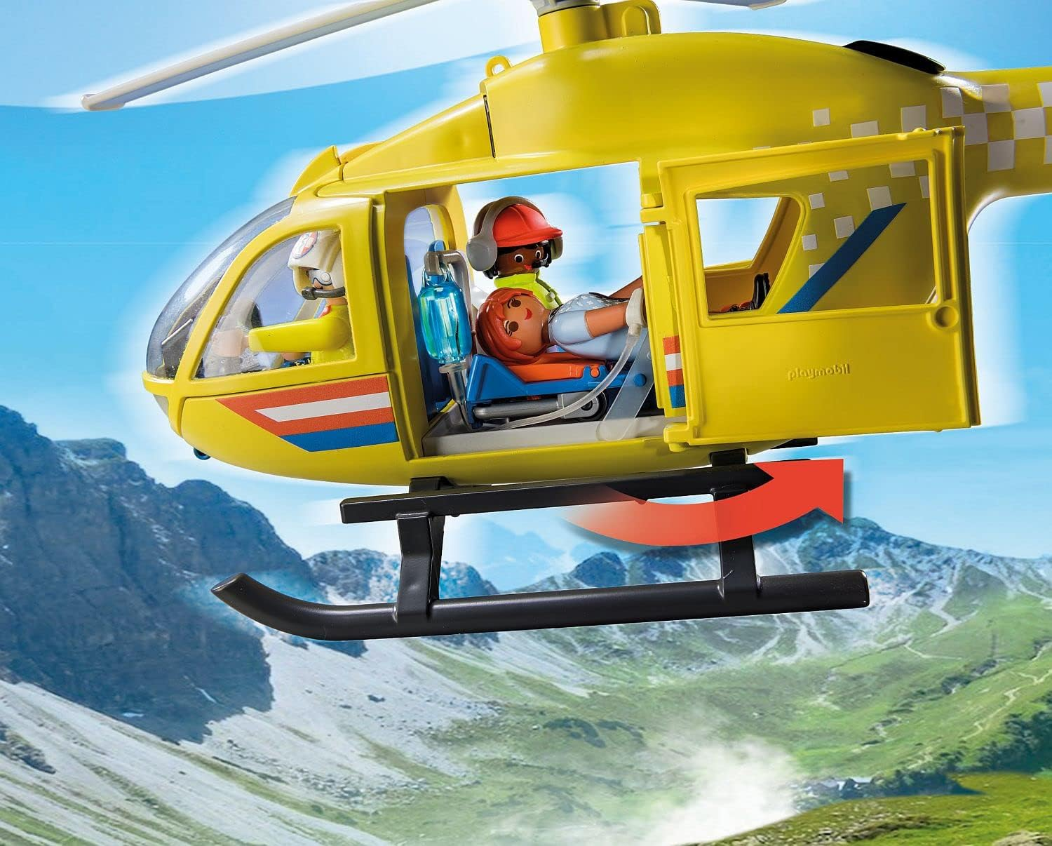 Żółty helikopter ratunkowy w locie, przewozi pacjenta i pilota, nad zielonymi górami.