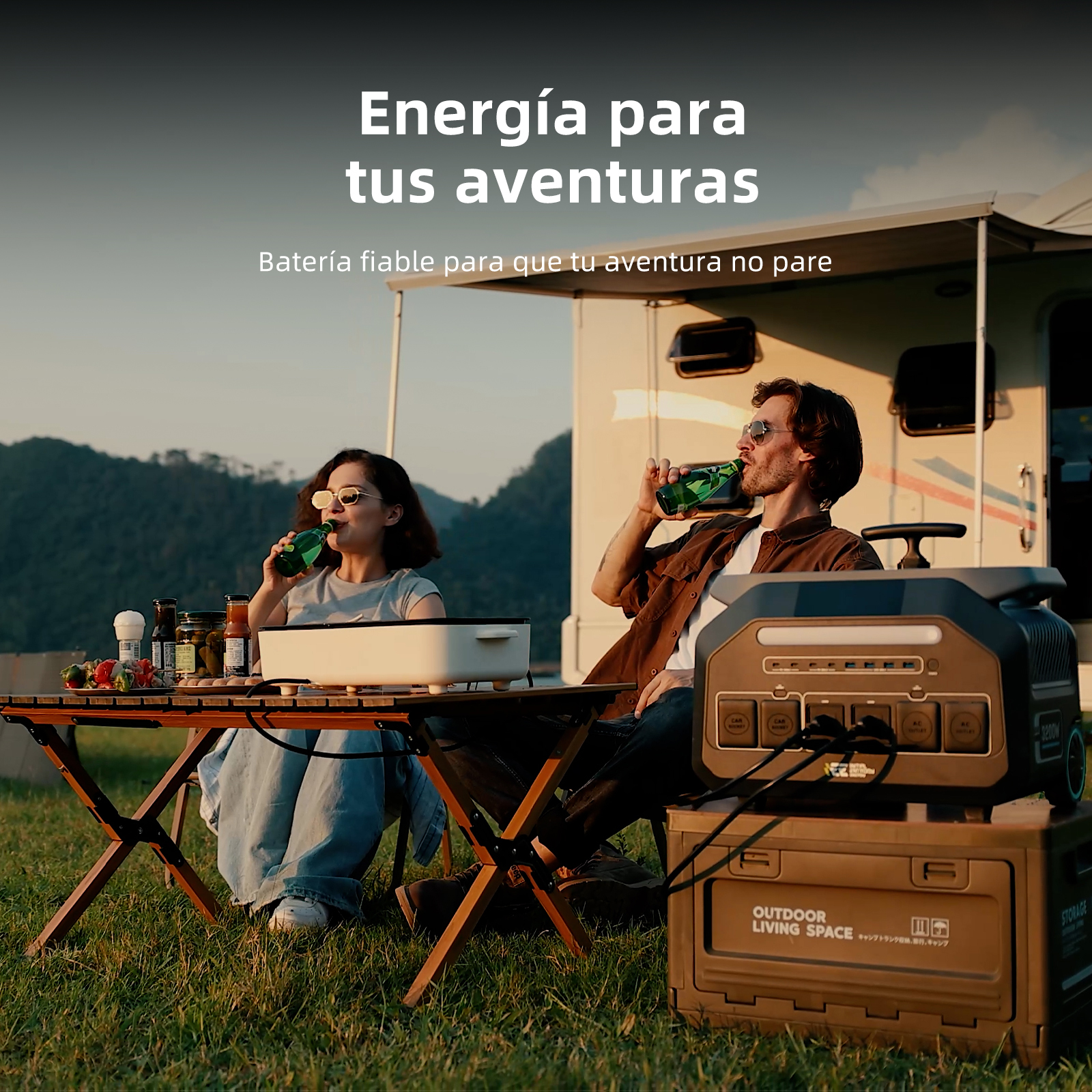 Dos personas beben cerveza frente a una caravana, con un generador y una mesa.