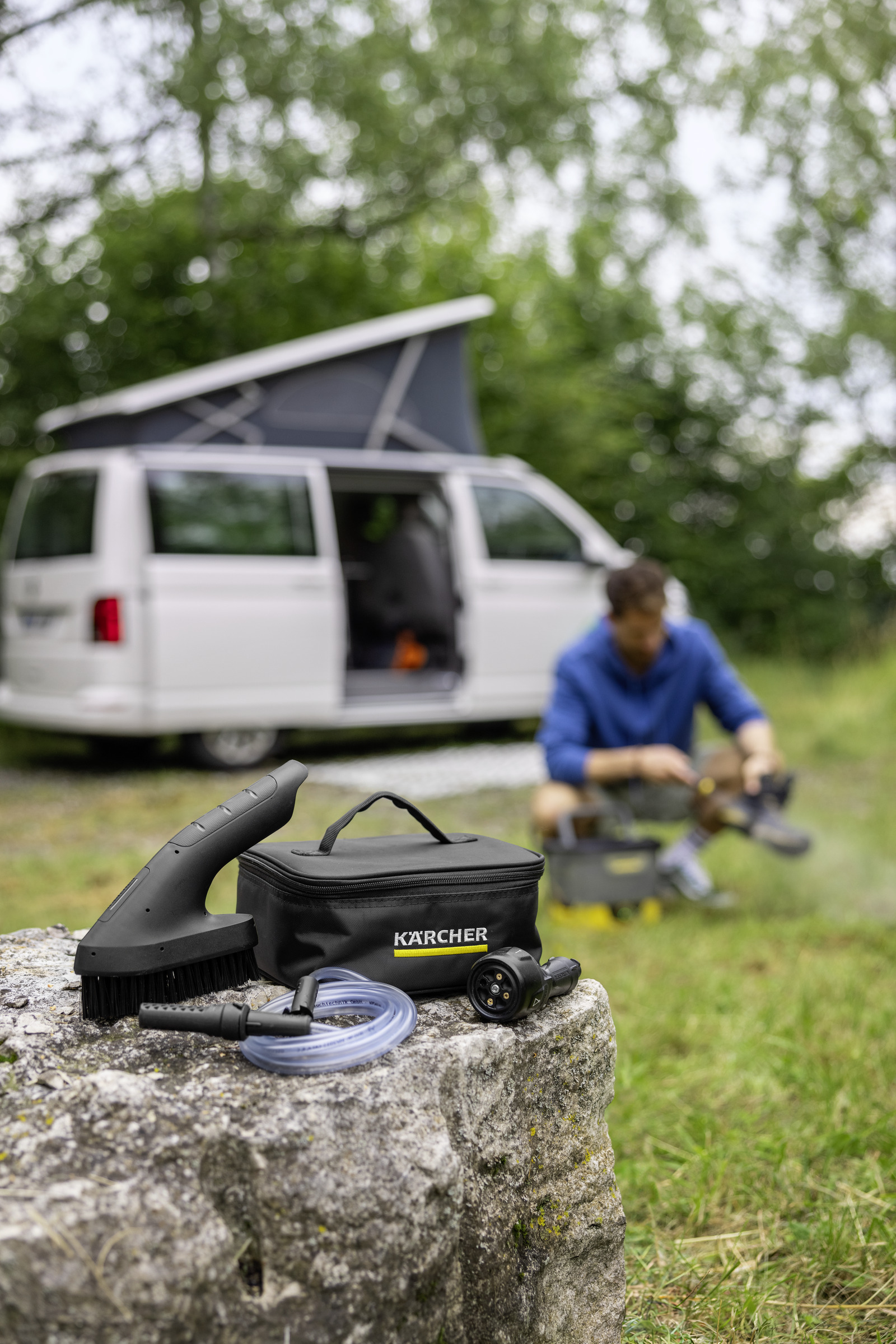Cleaning tools on rock near camper van and person.