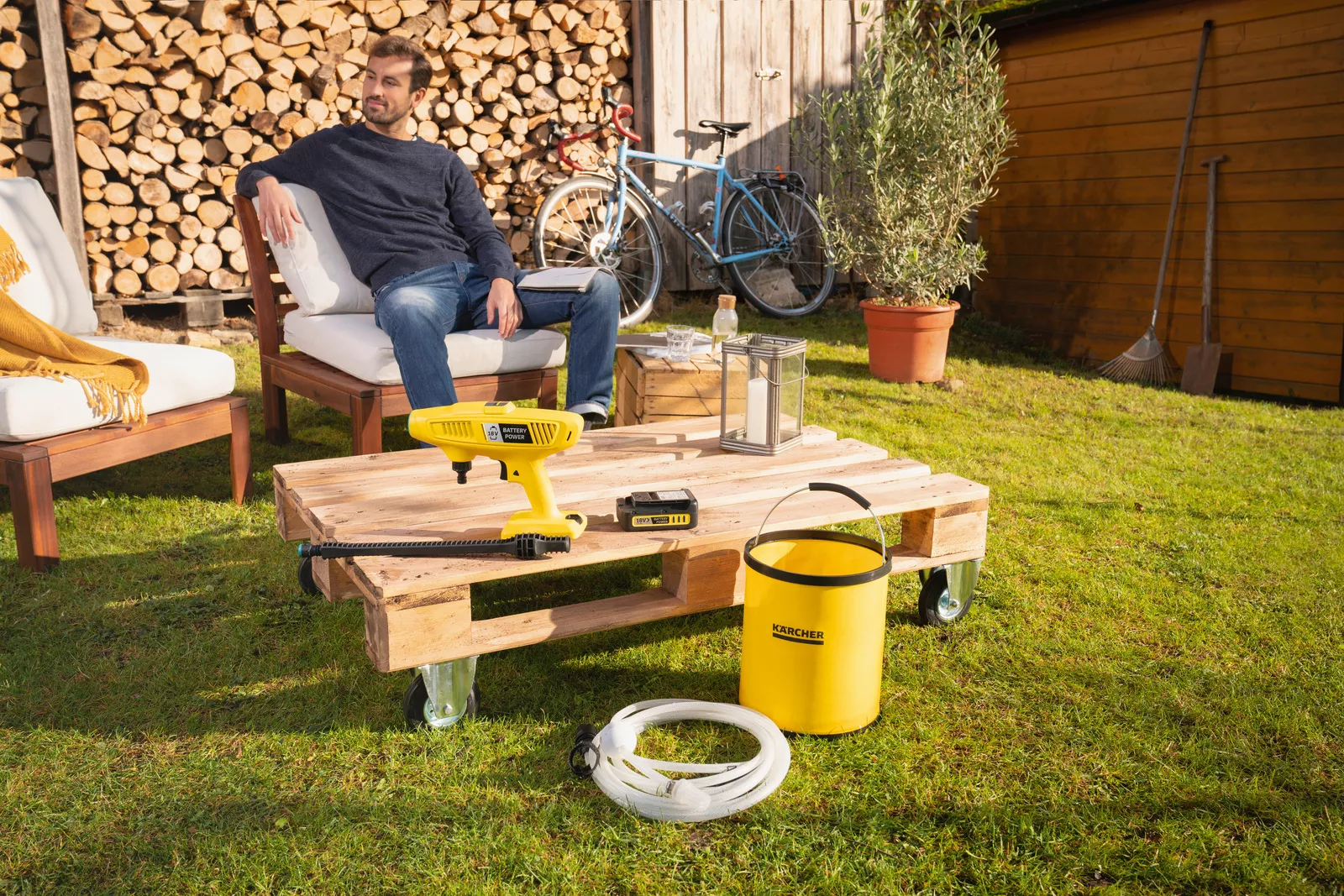 Man sits outdoors by a pallet table with Kärcher equipment.