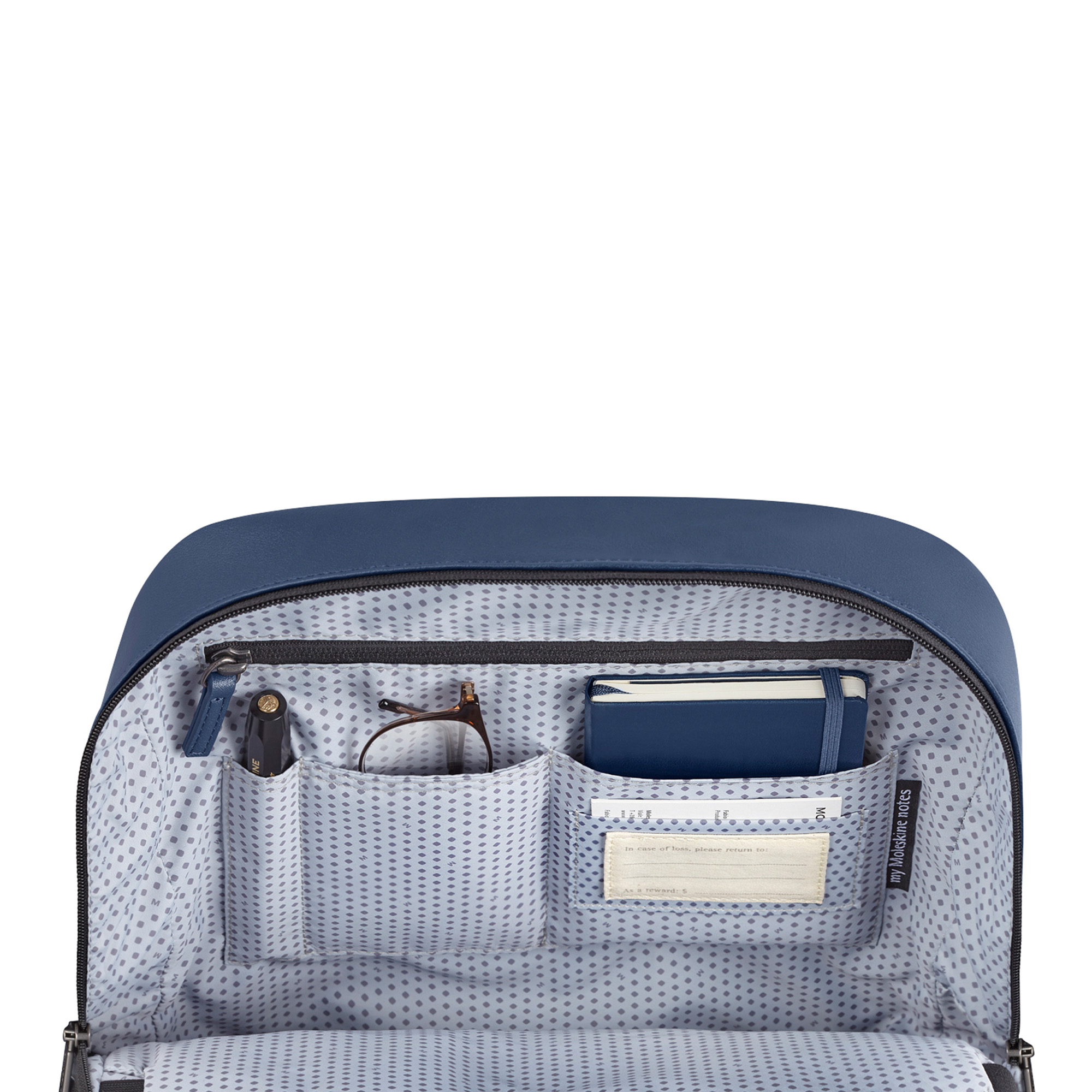 Borsa blu aperta con penna, occhiali, taccuino ed etichetta indirizzo.