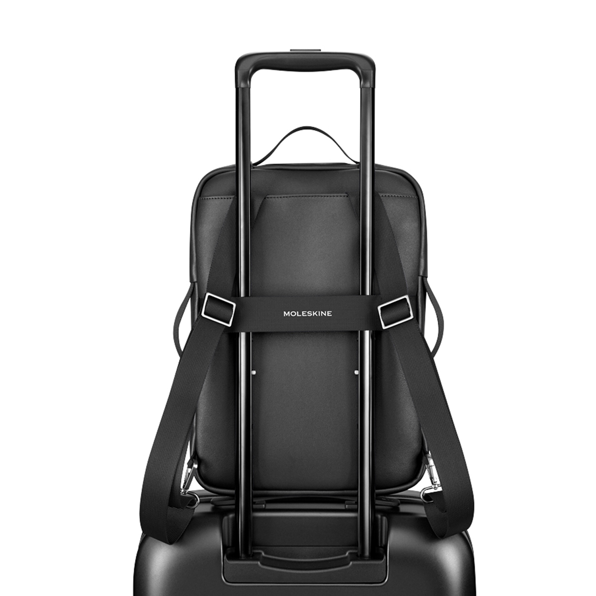Zaino nero con scritta "Moleskine", fissato al manico di un trolley.