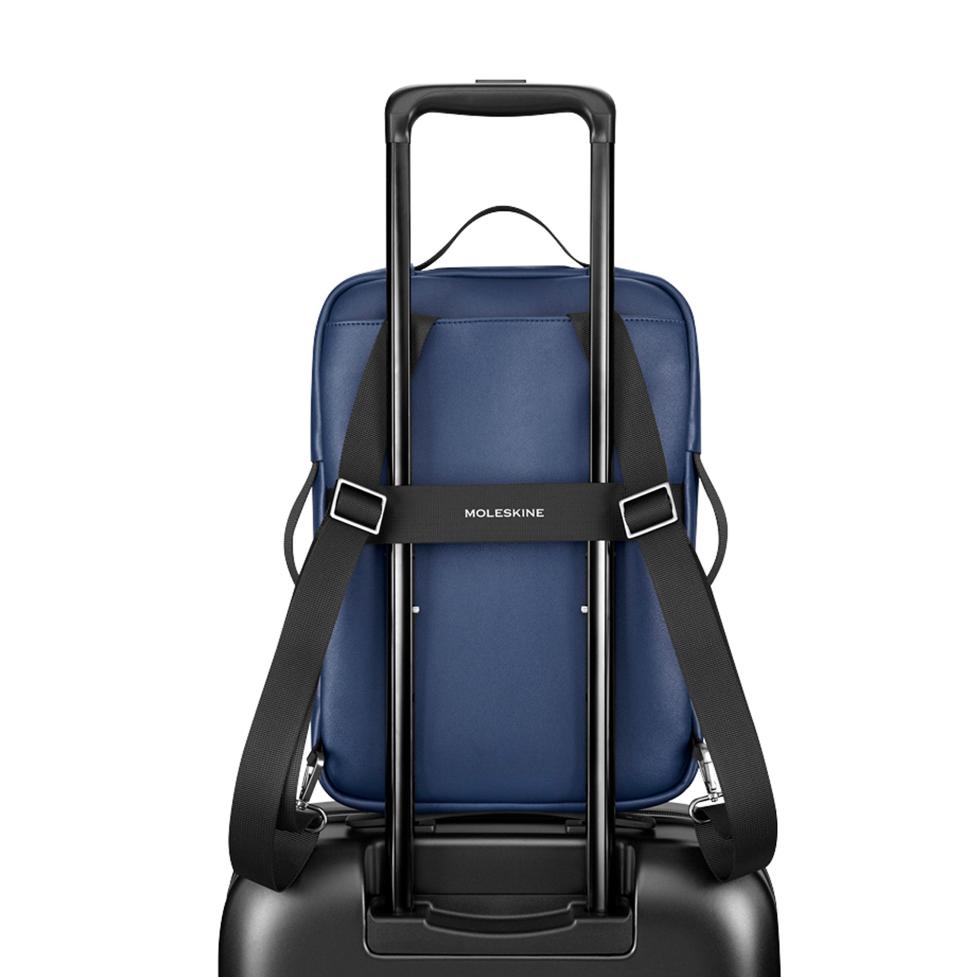 Una borsa blu Moleskine è attaccata a una valigia trolley nera.
