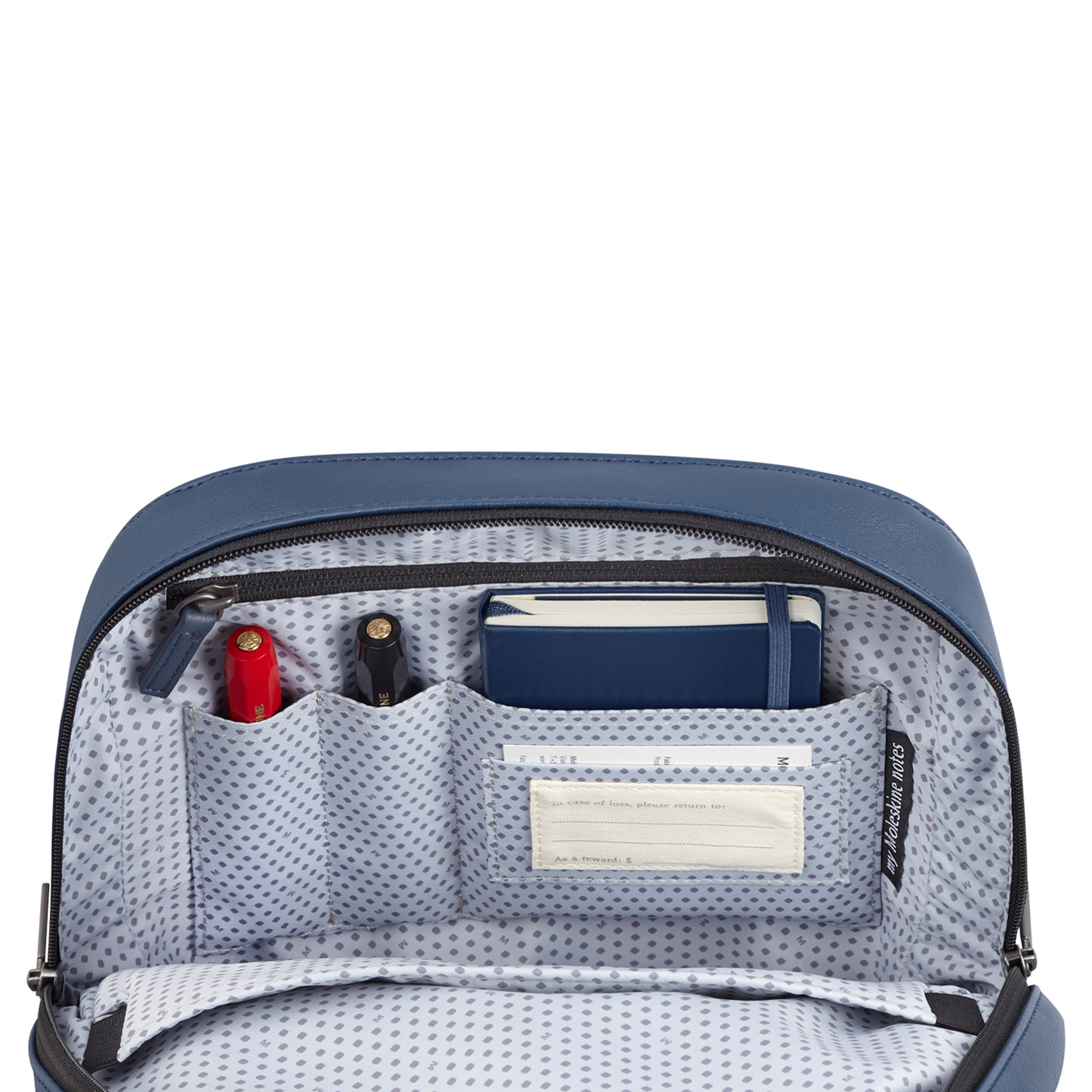 Interno borsa blu con penne, taccuino ed etichetta. Fodera a fantasia.