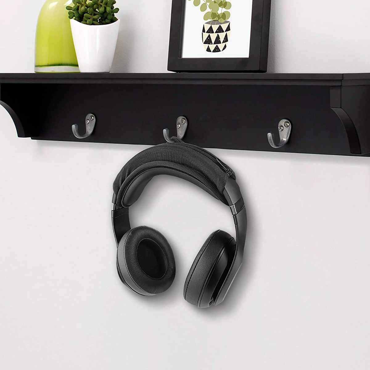 Cuffie nere appese a un gancio sotto una mensola con decorazioni.