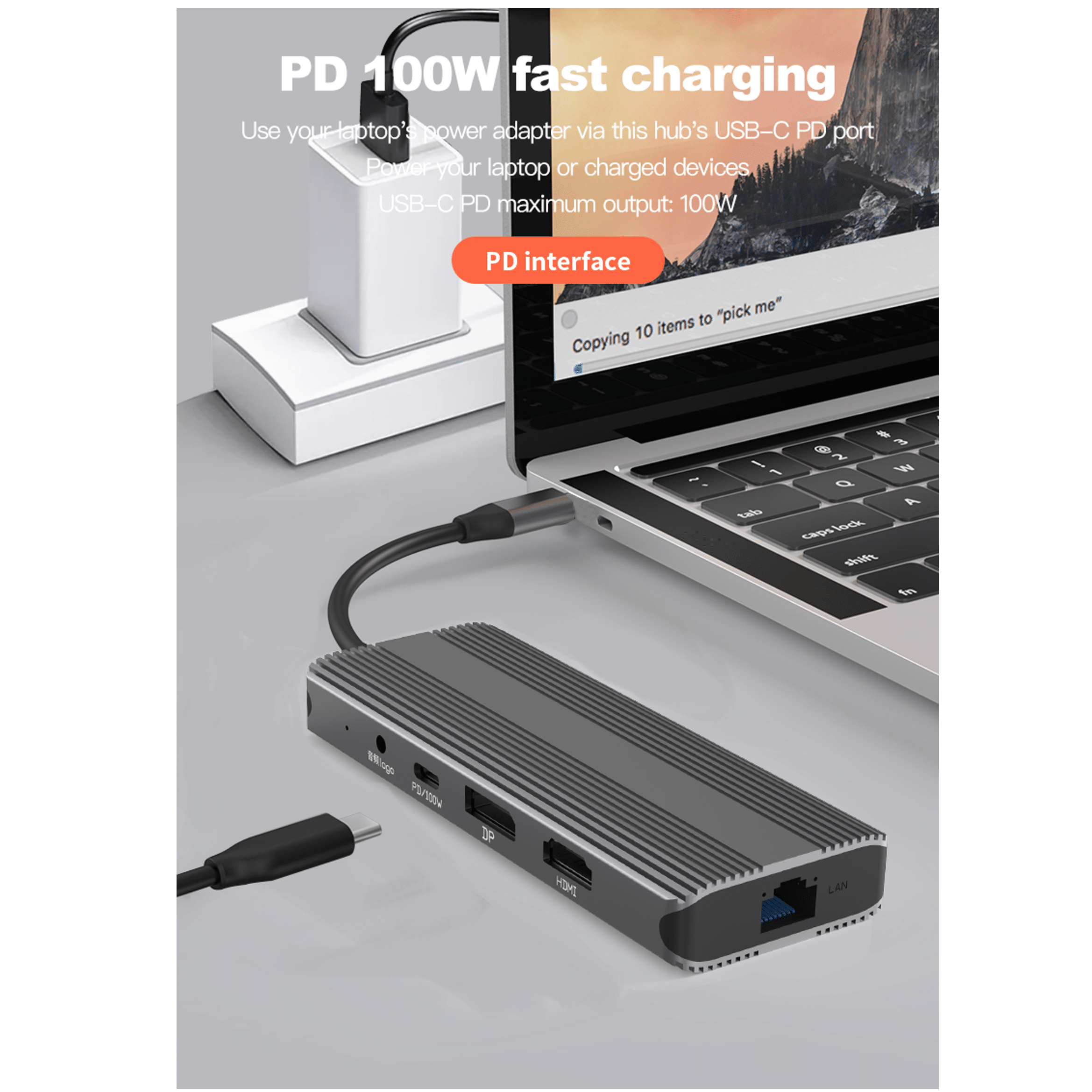 A gray USB-C hub with ports for laptop charging, DP, HDMI, and LAN, beside a laptop.