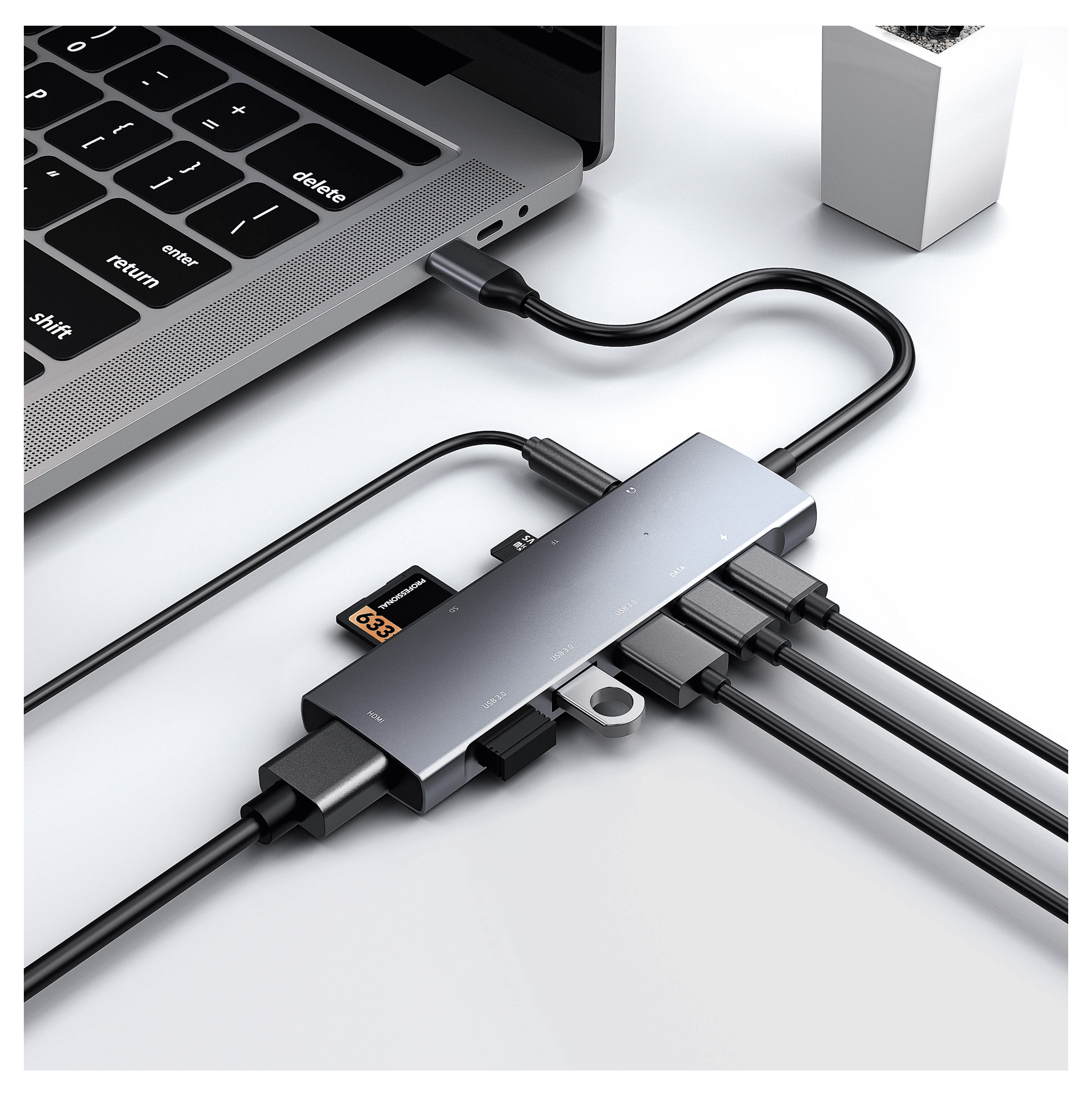Een USB-C hub is aangesloten op een grijze laptop. Hij heeft meerdere poorten.