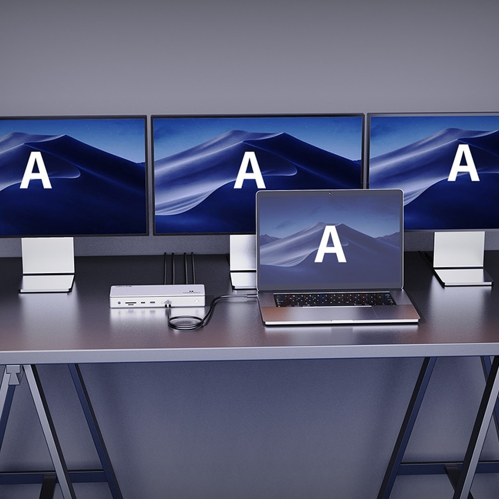 Een laptop en drie monitoren staan op een bureau met een docking station.