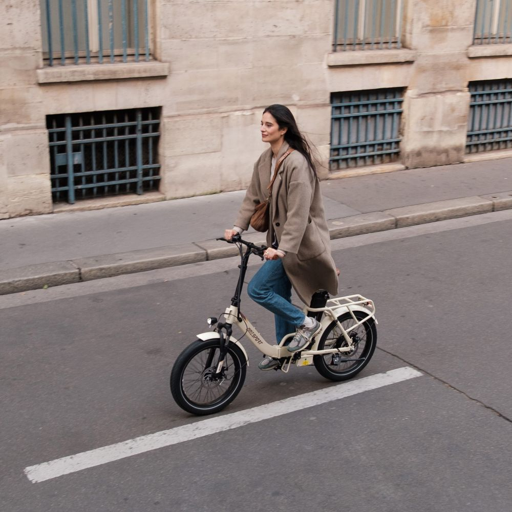 Una mujer monta en bicicleta beige por una calle de la ciudad.