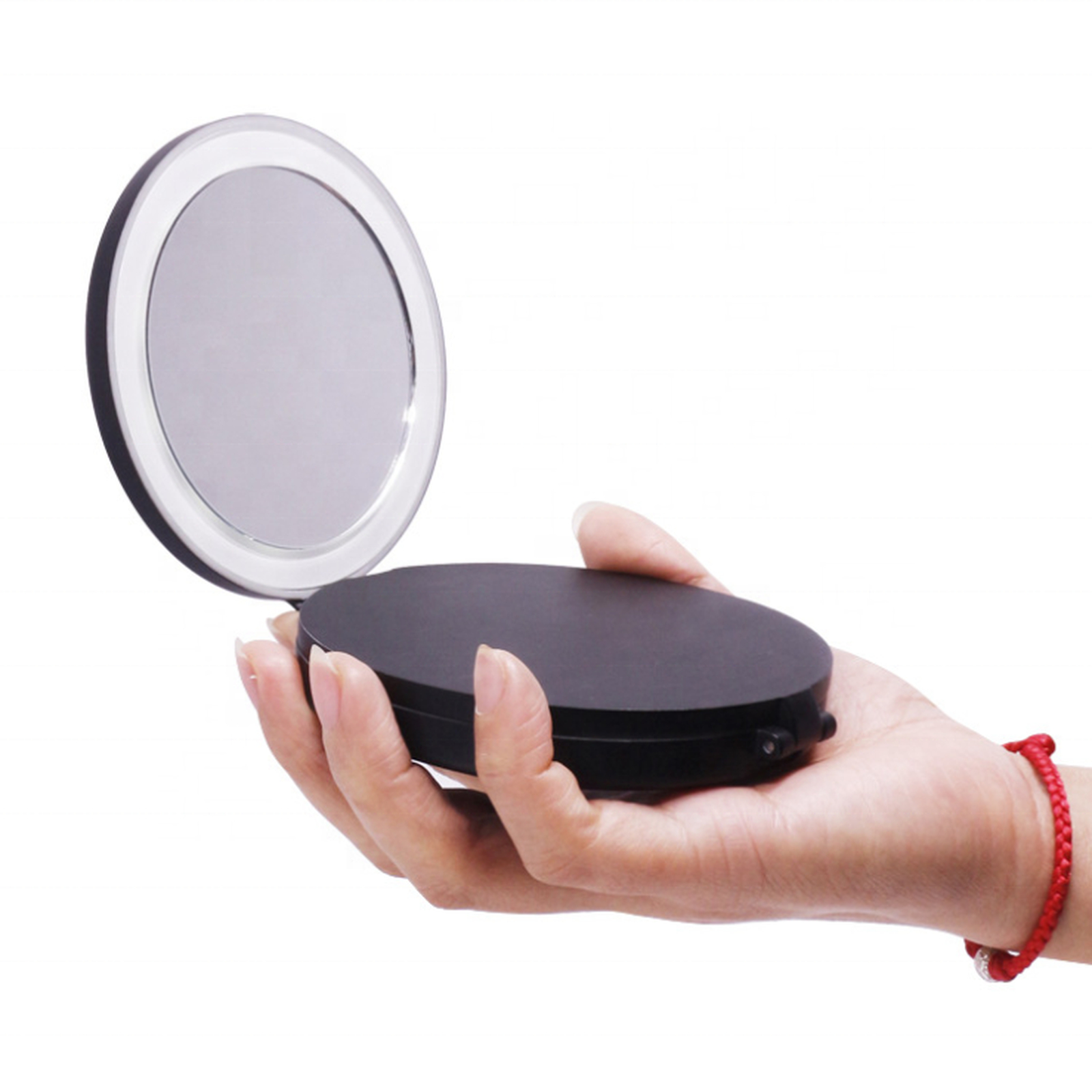 Una mano tiene uno specchio compatto nero aperto con luce LED.