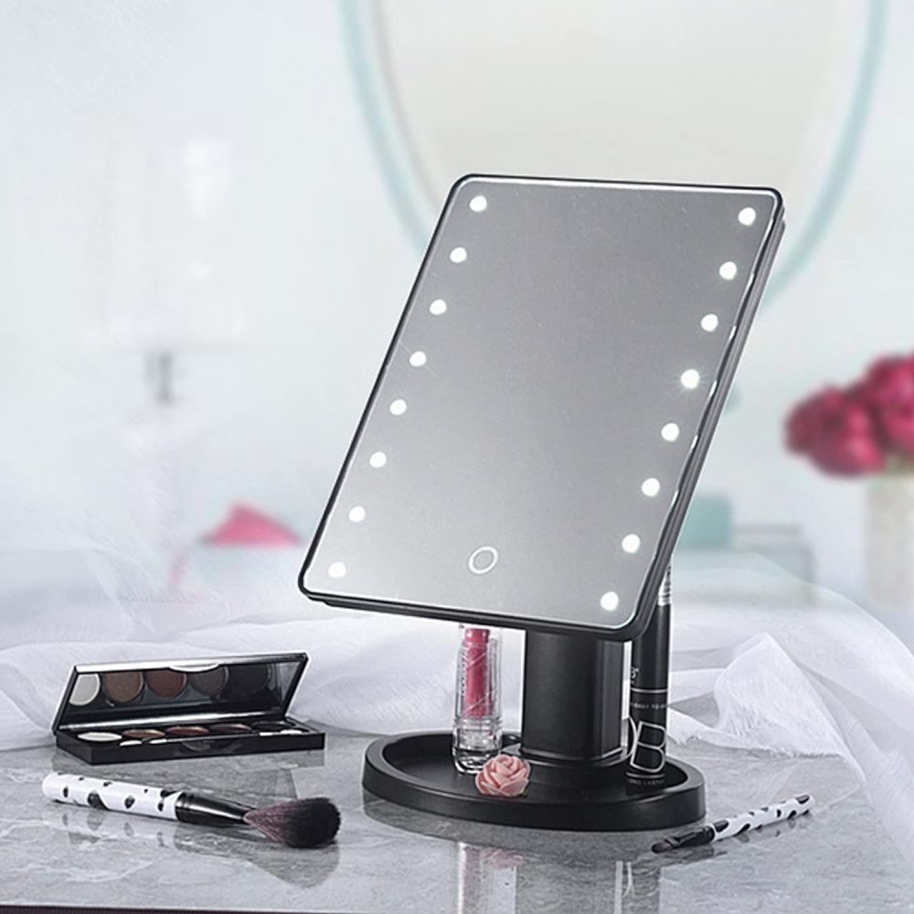 Uno specchio per il trucco illuminato con pennelli, palette di ombretti e rossetto.