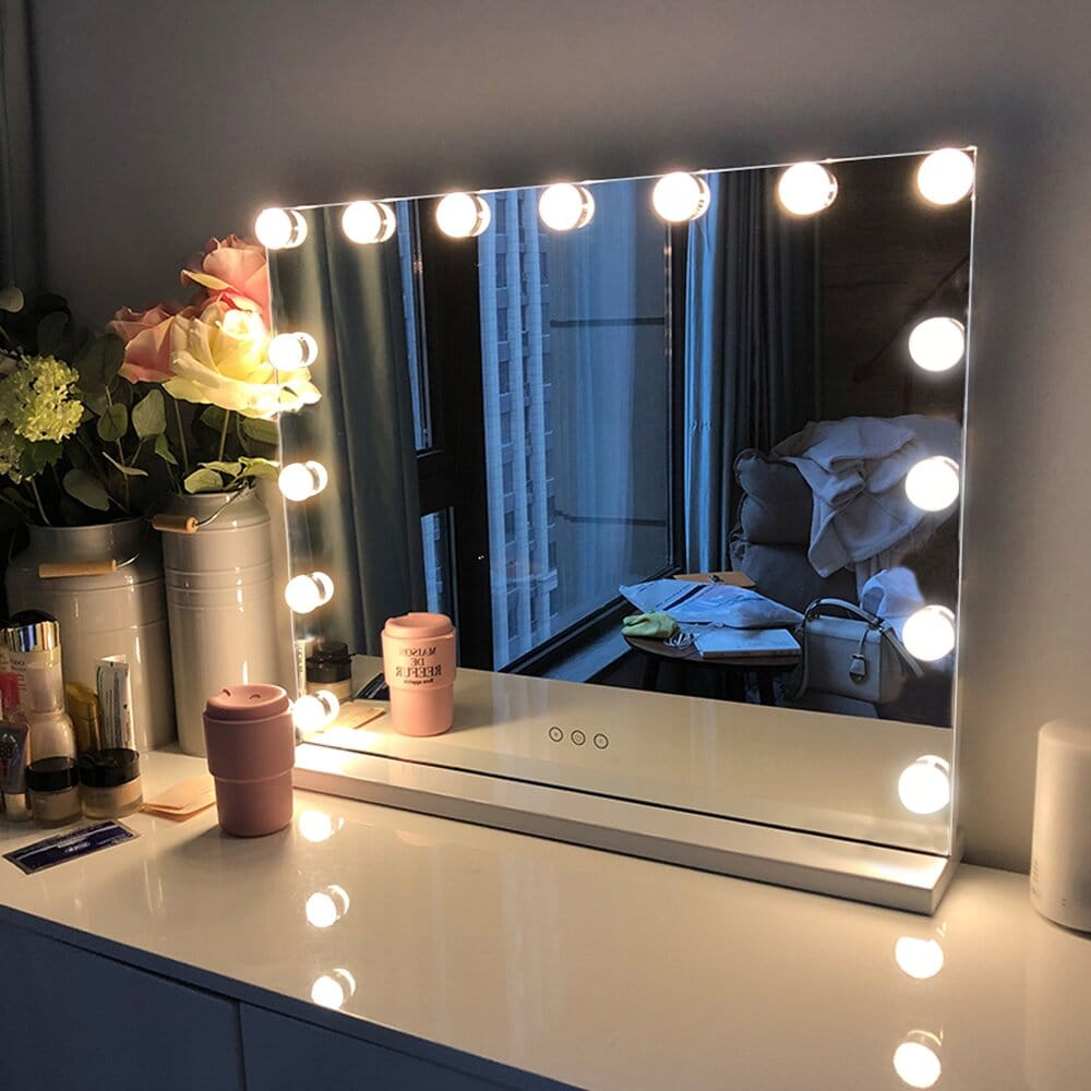 Specchio da toeletta con luci, fiori e trucchi su una cassettiera.